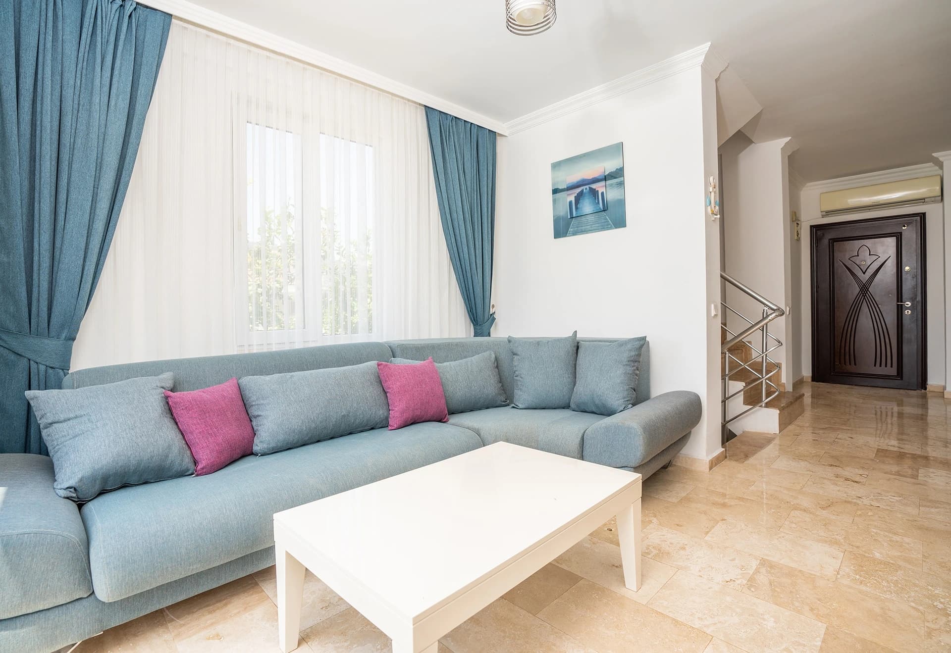 Spacious living room with comfortable sectional sofa and abundant natural light from floor-to-ceiling windows.