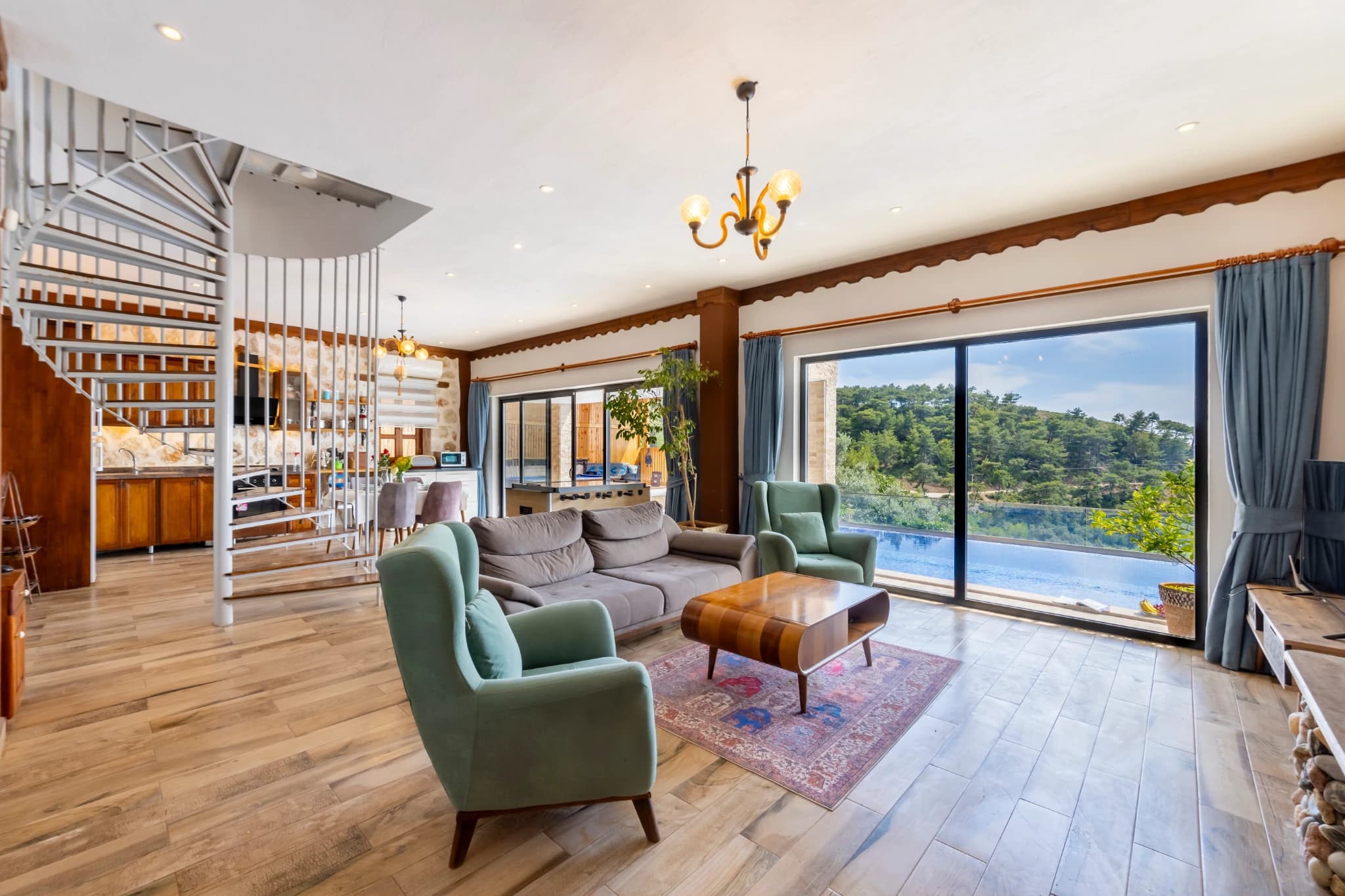Spacious open-plan living room with floor-to-ceiling windows overlooking the blue pool and landscape.