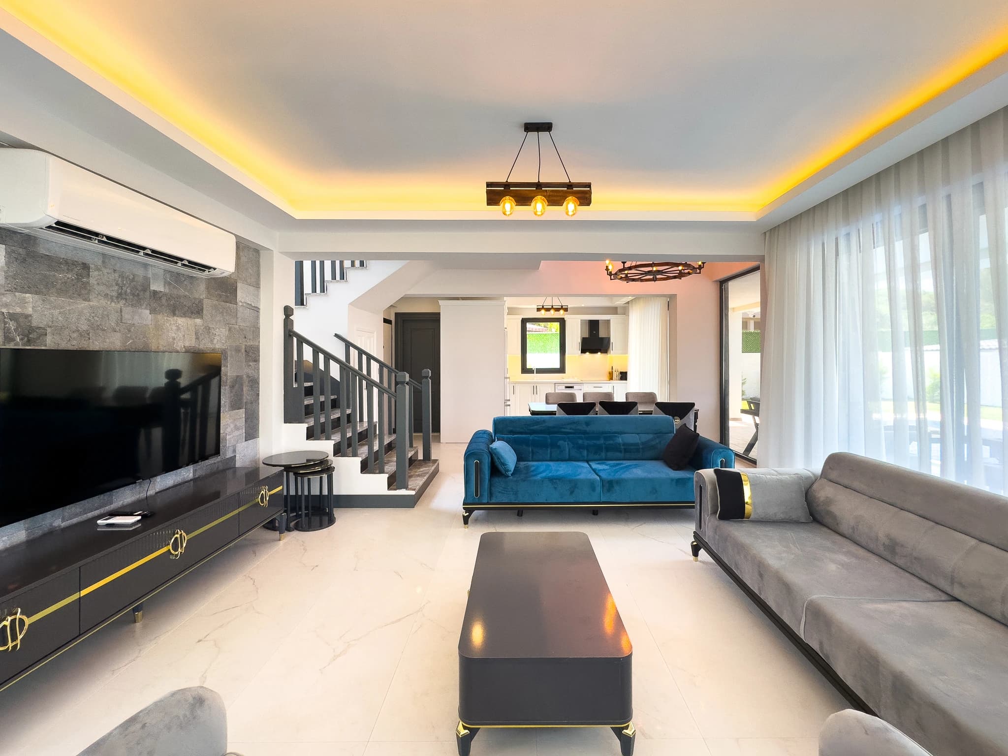 Spacious modern living room with multiple seating areas, accent lighting, and contemporary furnishings.