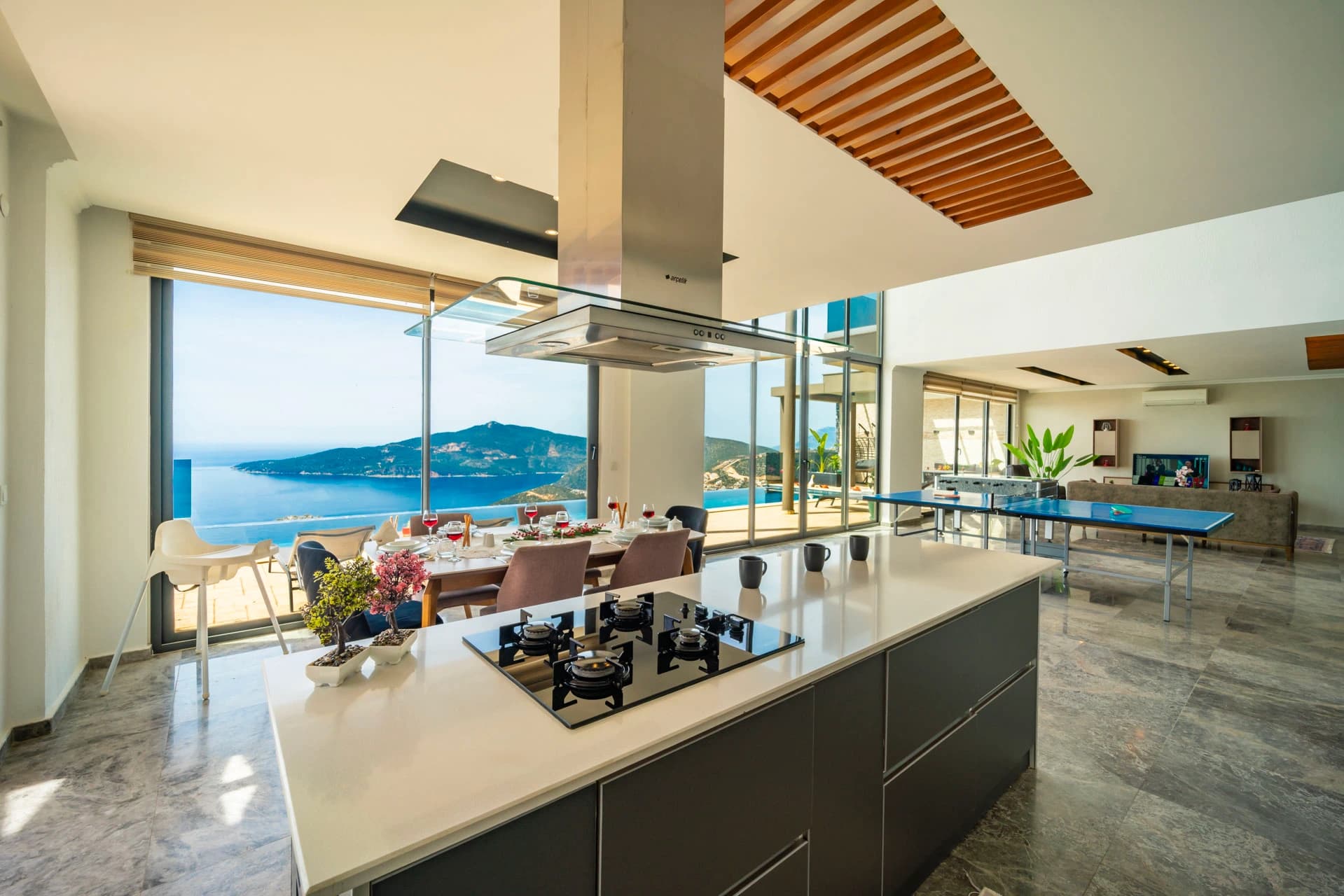 Modern kitchen with island and spectacular sea views through floor-to-ceiling windows.