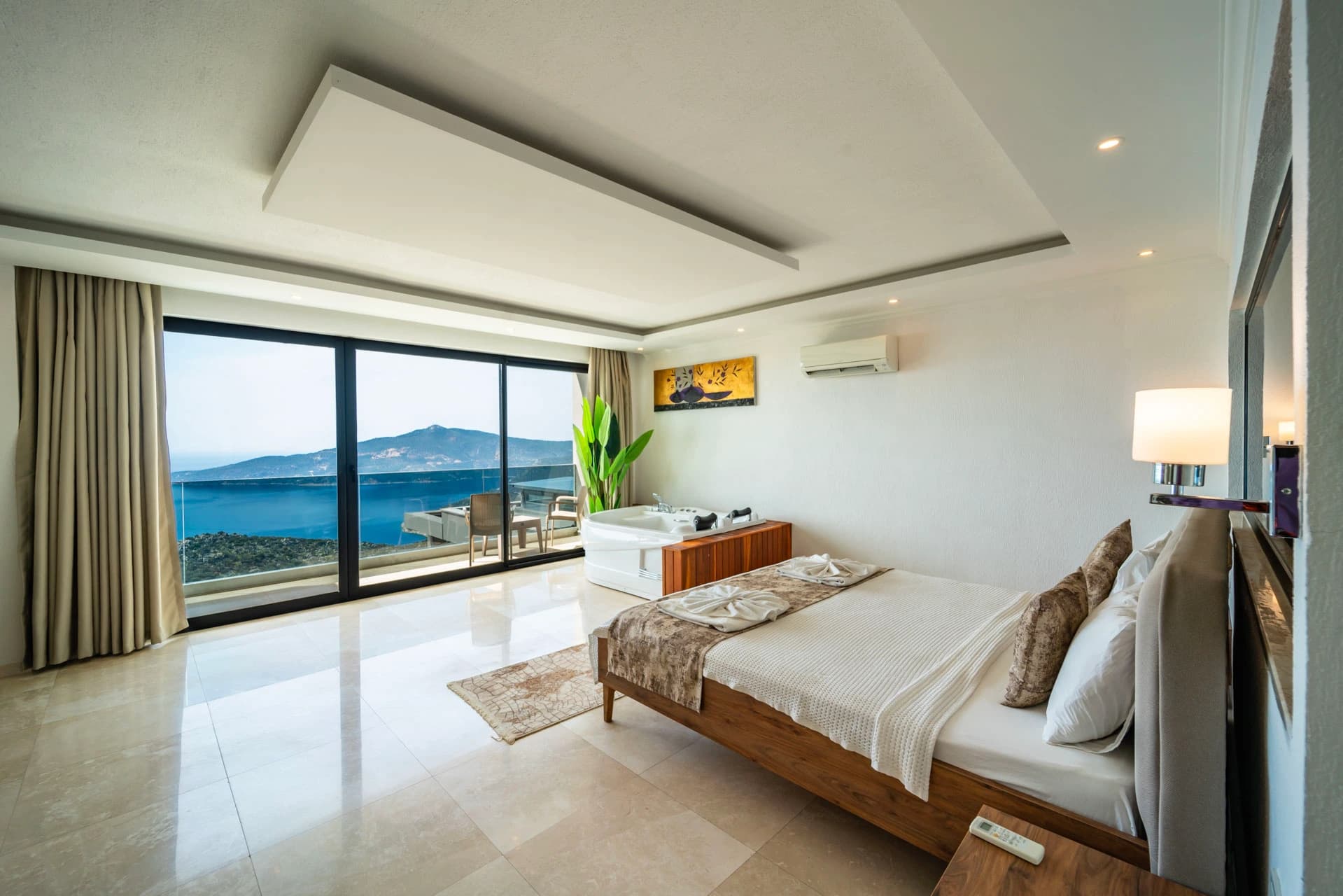Spacious master bedroom with panoramic sea and mountain views through floor-to-ceiling windows.