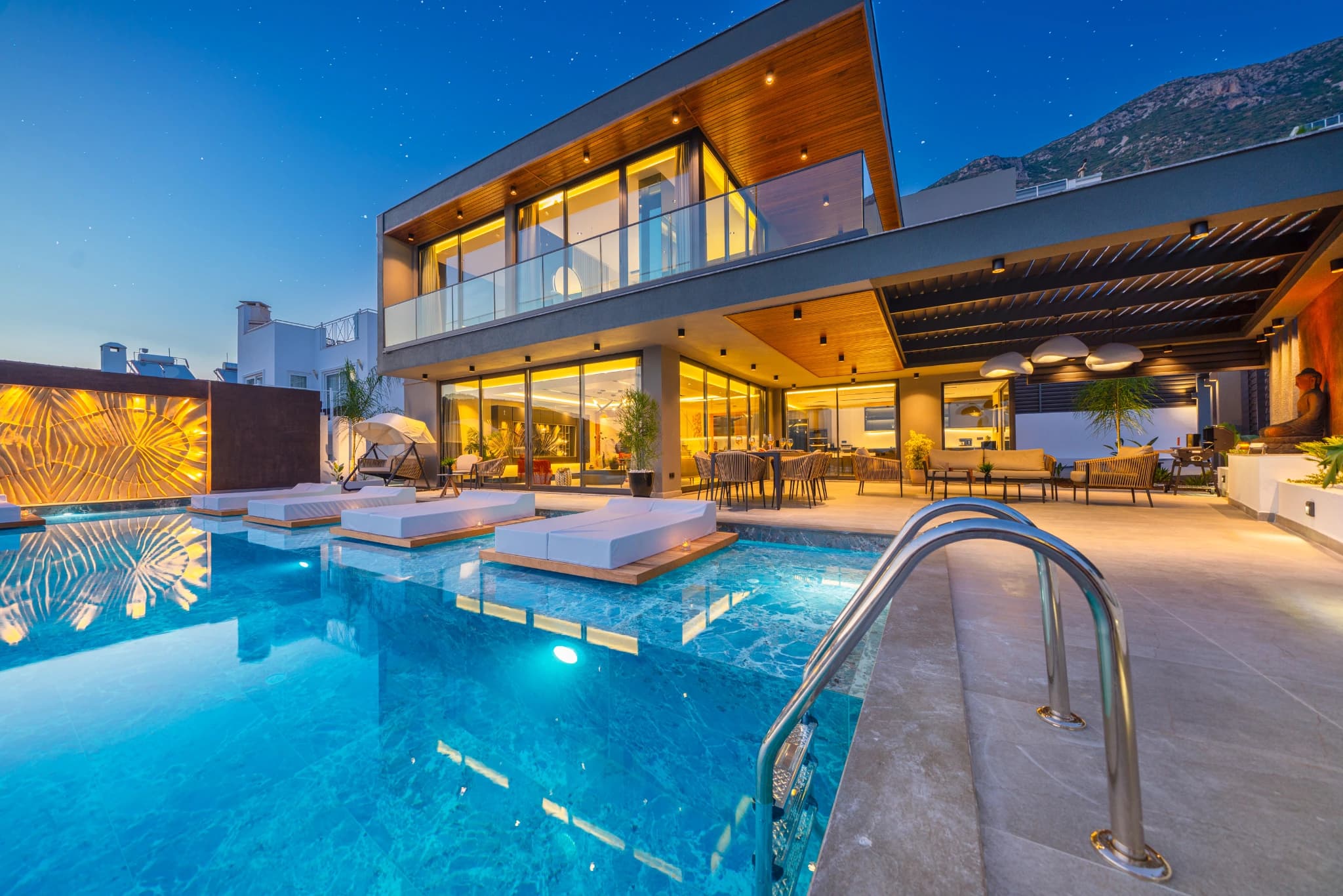 Stunning infinity pool with panoramic sea and mountain views at dusk.