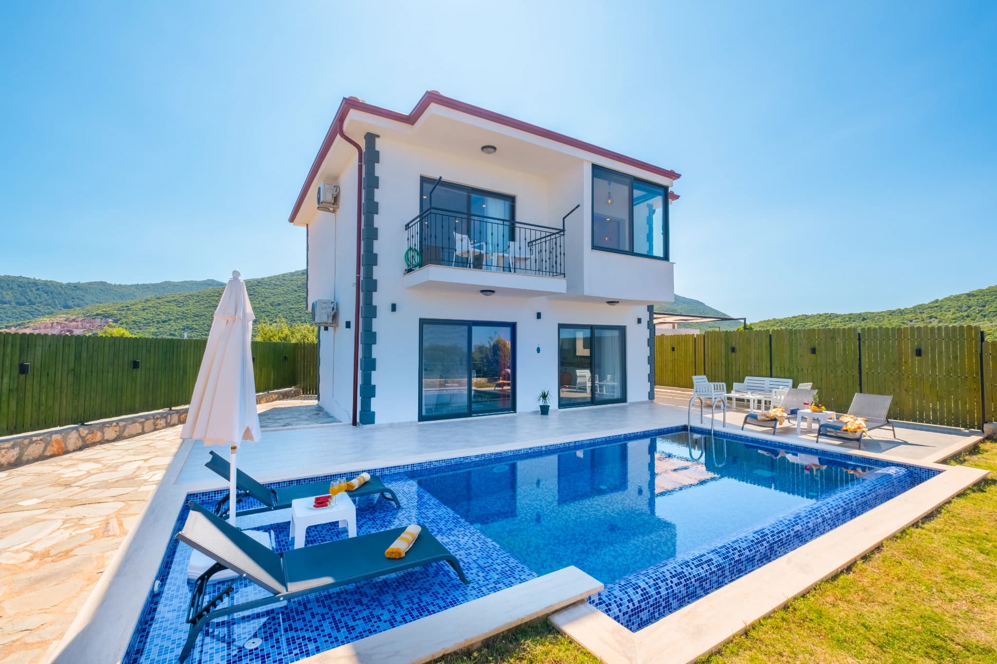 Contemporary villa featuring private pool with lounging area and mountain backdrop.