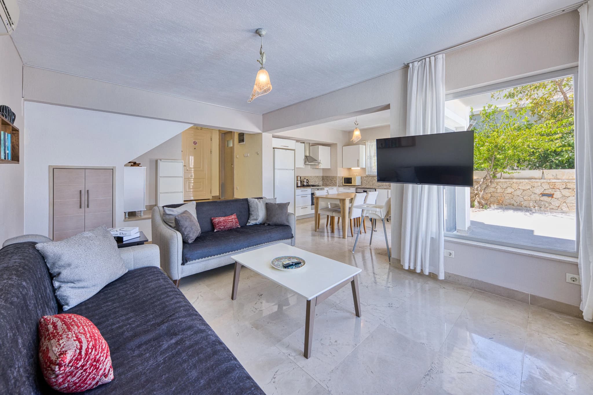 Bright open-plan living area with comfortable seating, smart TV, and garden access.