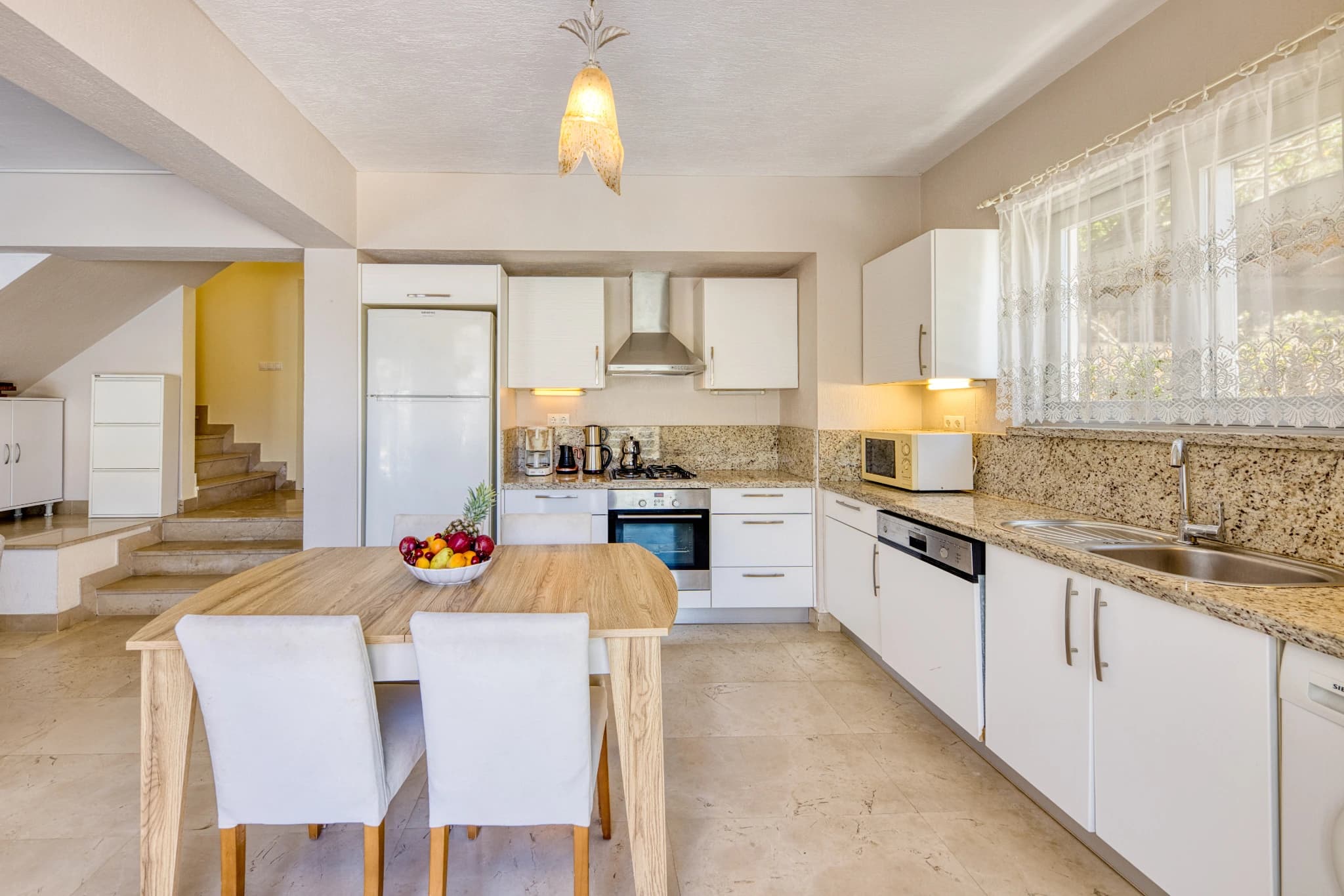 Alternative kitchen angle showing island prep area and staircase access.
