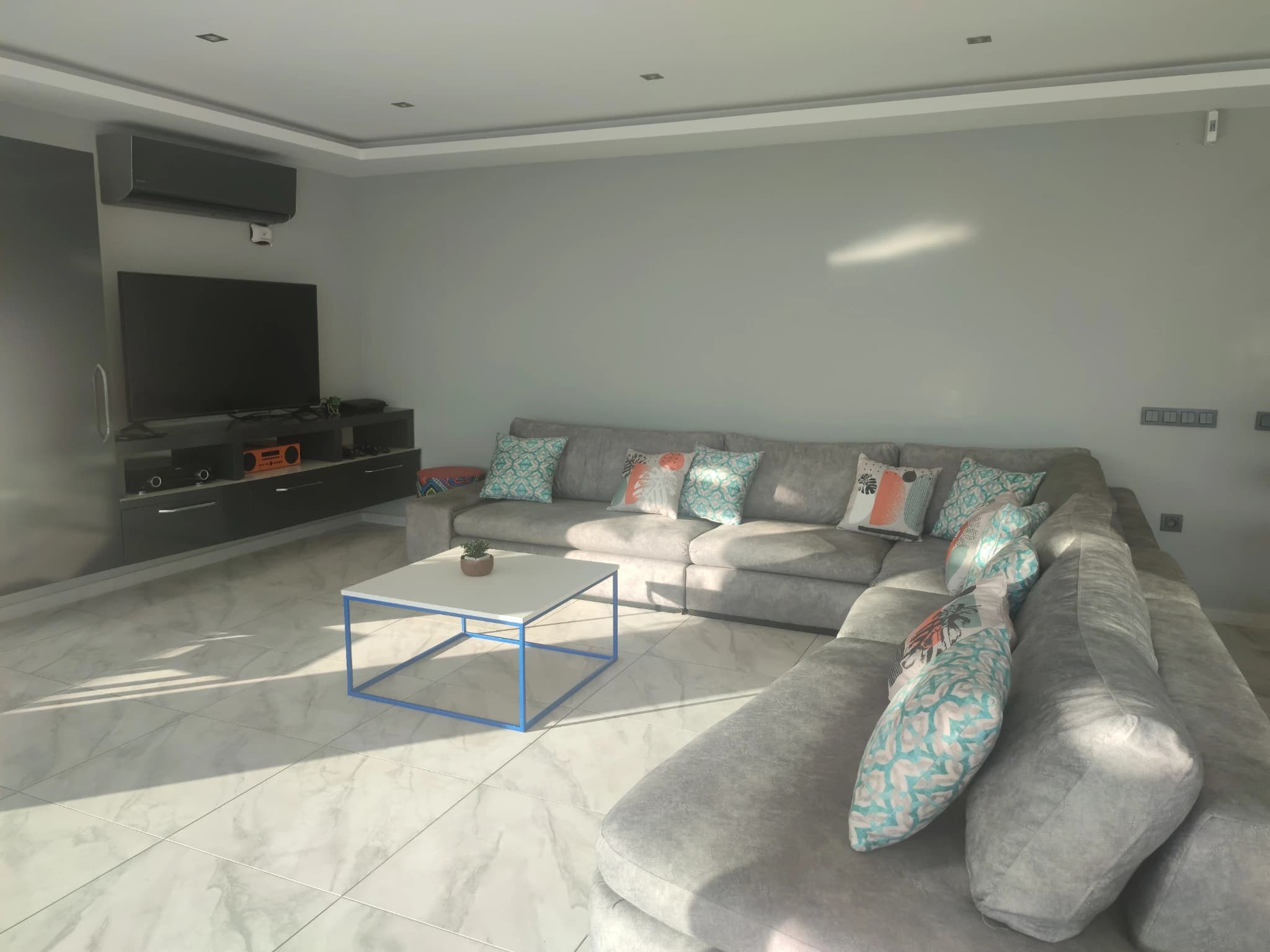 Spacious lounge area with sectional sofa and wall-mounted TV.
