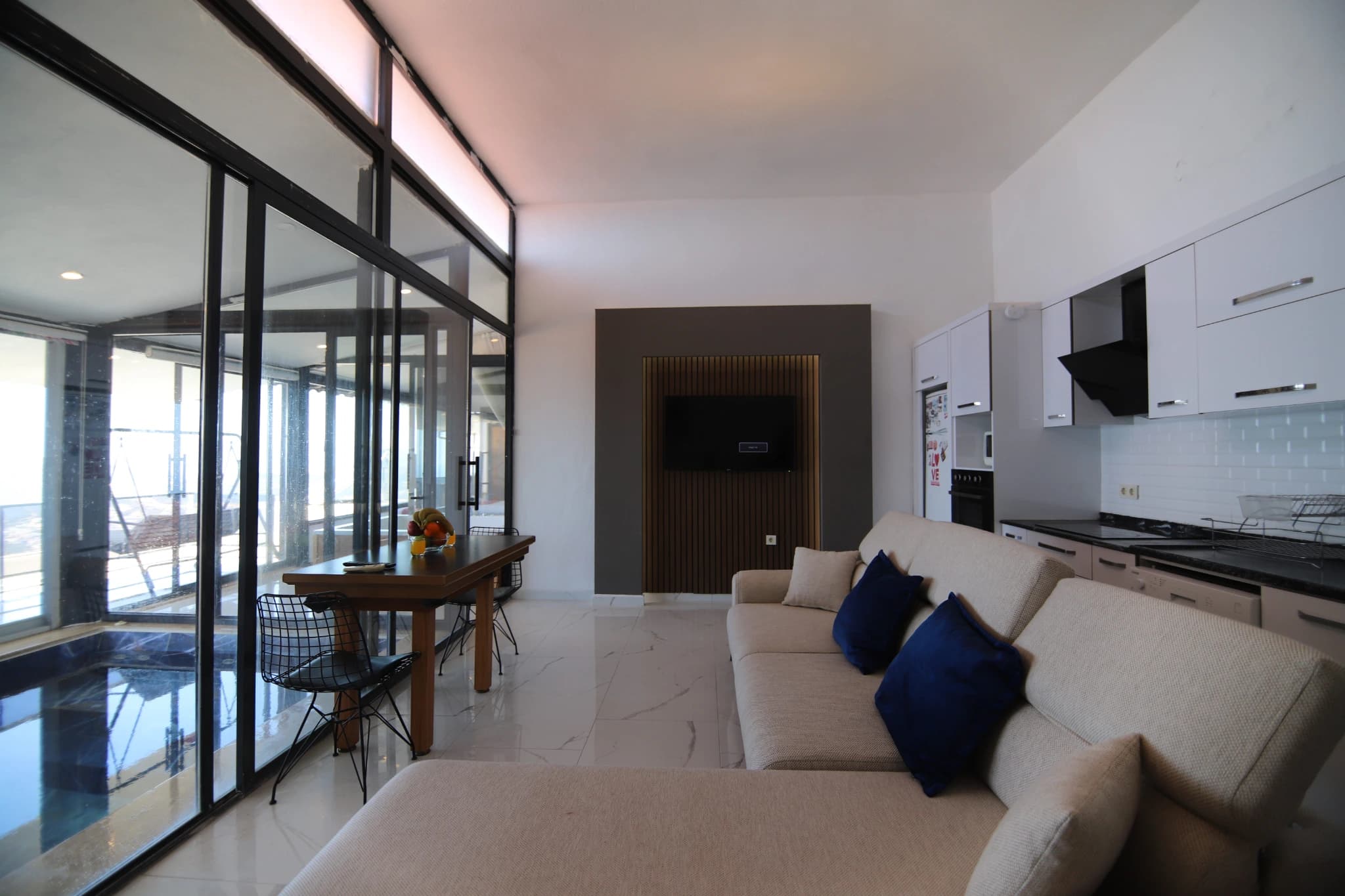 Open-plan living and kitchen area with sea views and minimalist modern furnishings.