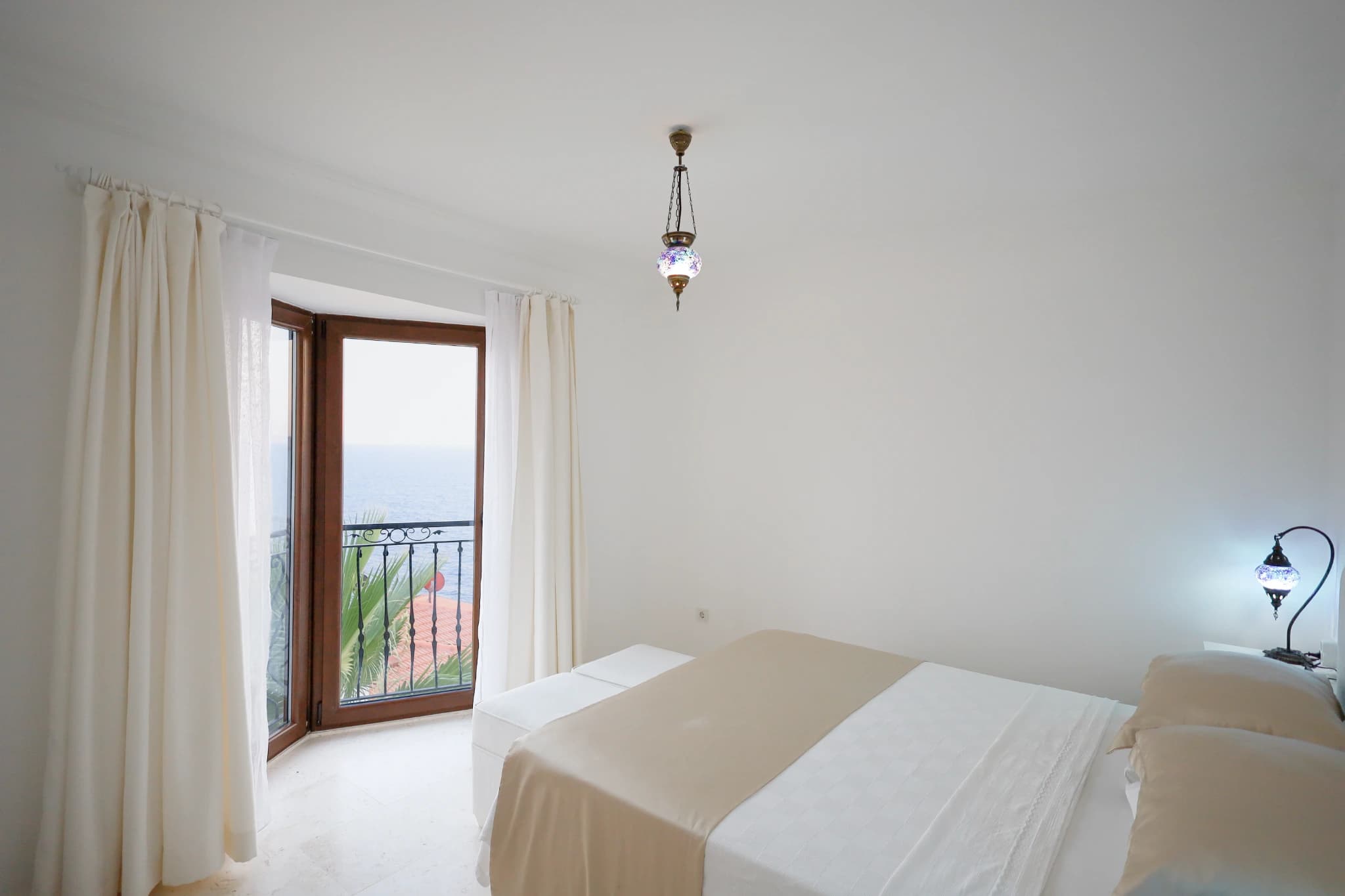 Bright bedroom with king bed and balcony overlooking the sea.