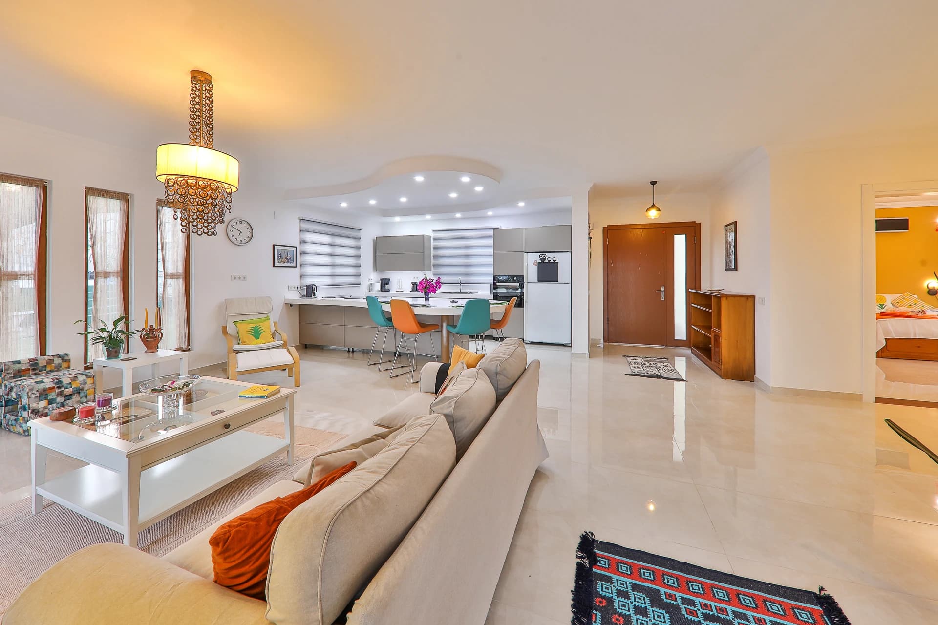 Open-plan living room with comfortable seating, modern lighting, and integrated dining and kitchen areas.