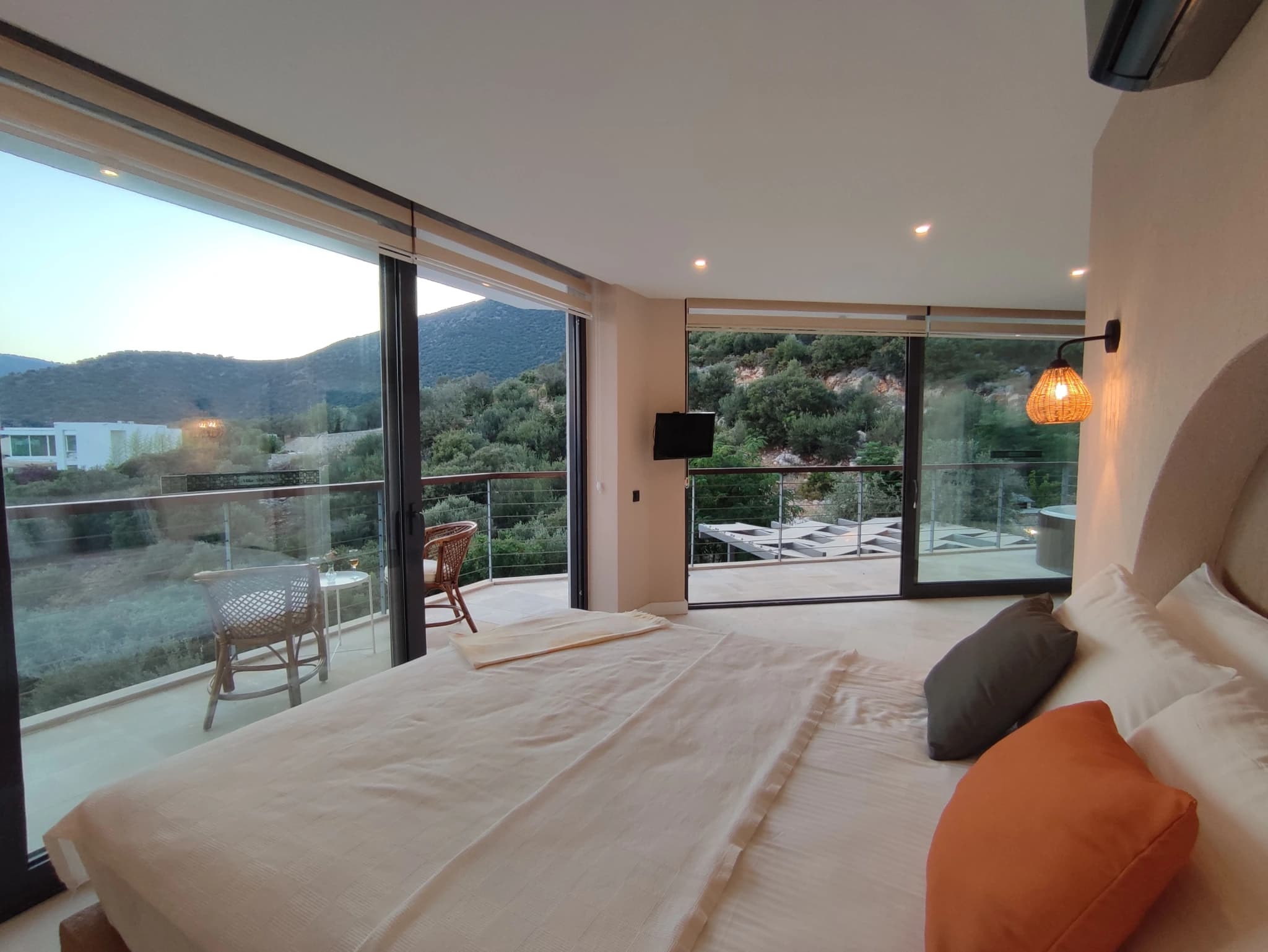 Spacious bedroom with king bed, wall-mounted TV, and large sliding doors opening to mountain views.