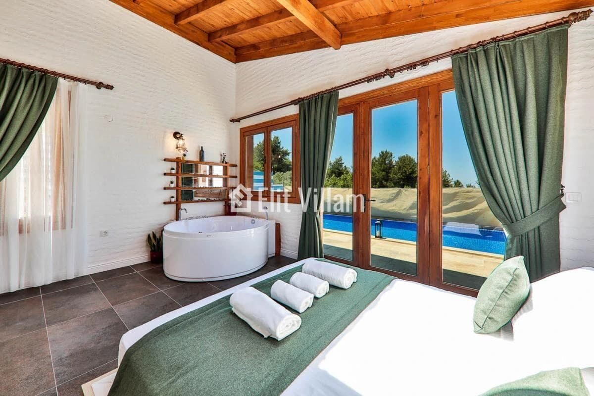 Spacious bedroom suite with king bed, freestanding bathtub, pool view, and glass doors to terrace.
