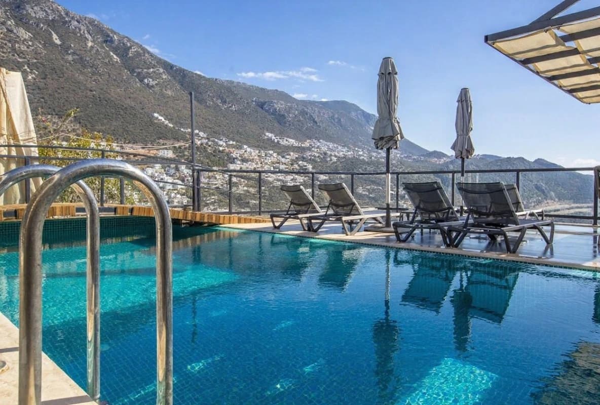 Crystal-clear pool with lounging area and stunning mountain vistas in the background.