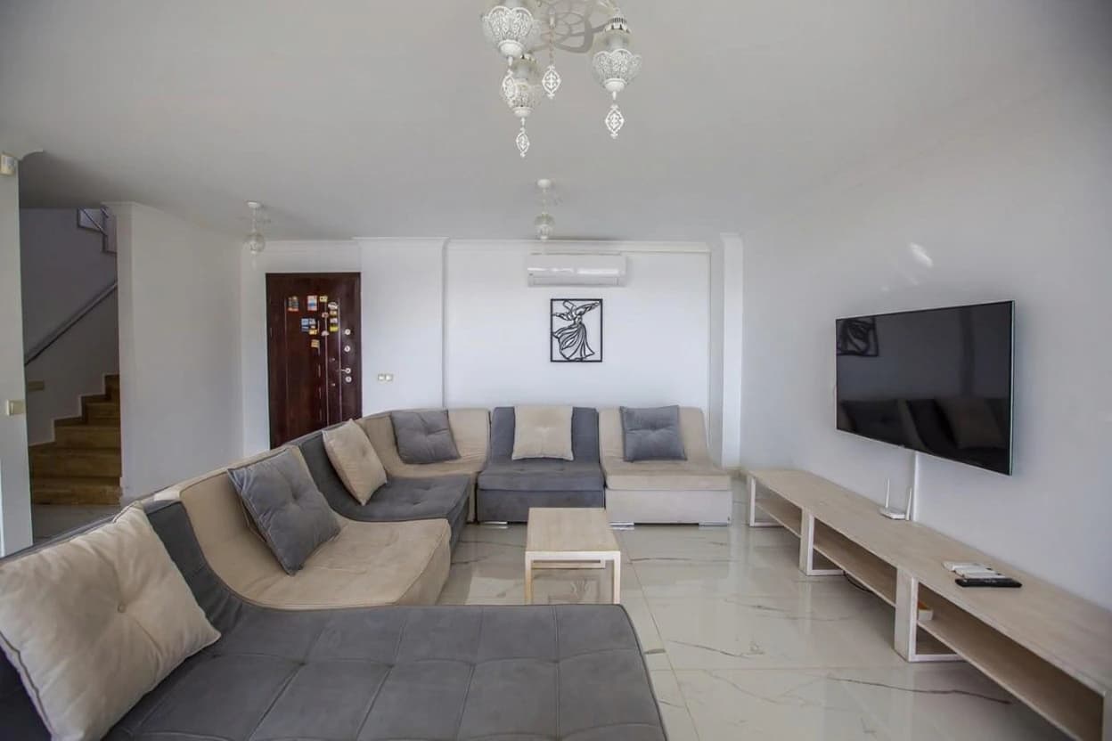 Spacious modern living room with oversized sectional sofa and flat-screen television.