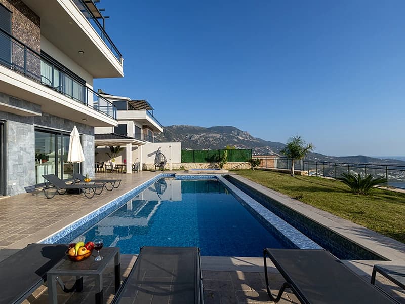 Stunning private pool with mountain backdrop and multiple sun loungers on expansive terrace.