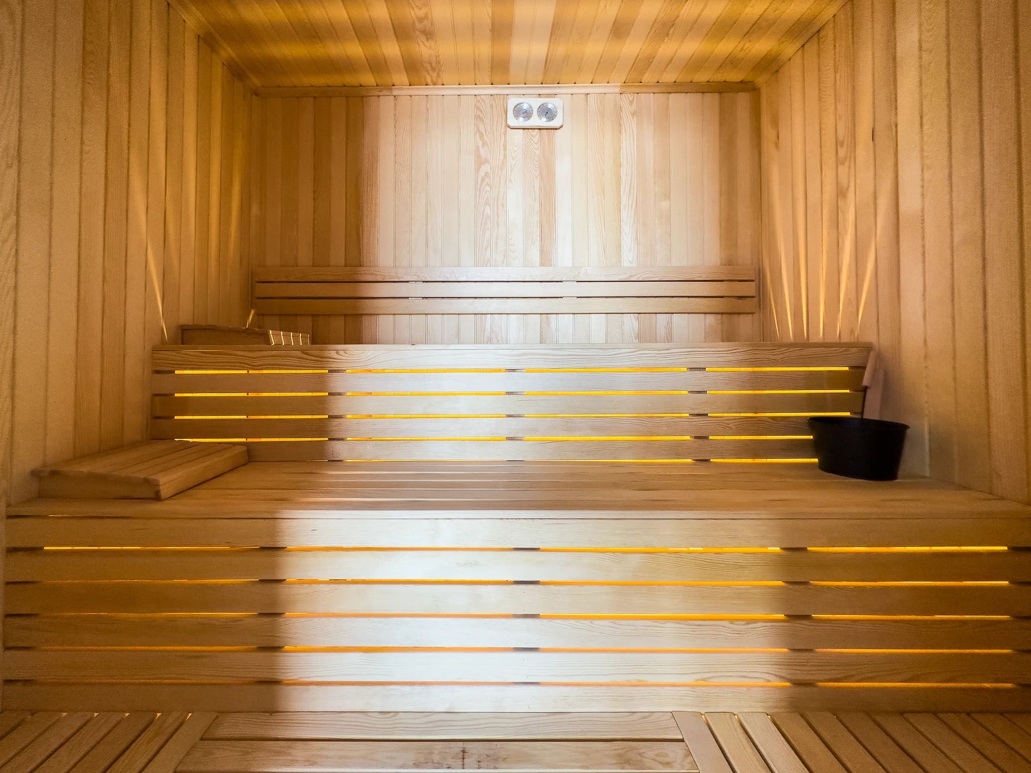 Private sauna with heated wooden benches and ambient infrared lighting.