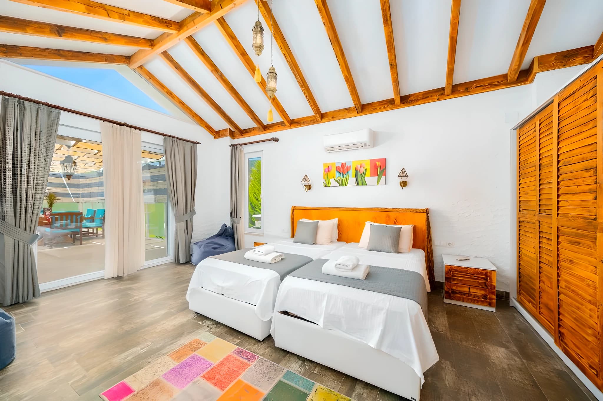 Spacious bedroom with twin beds, exposed wooden beams, and direct access to garden terrace.