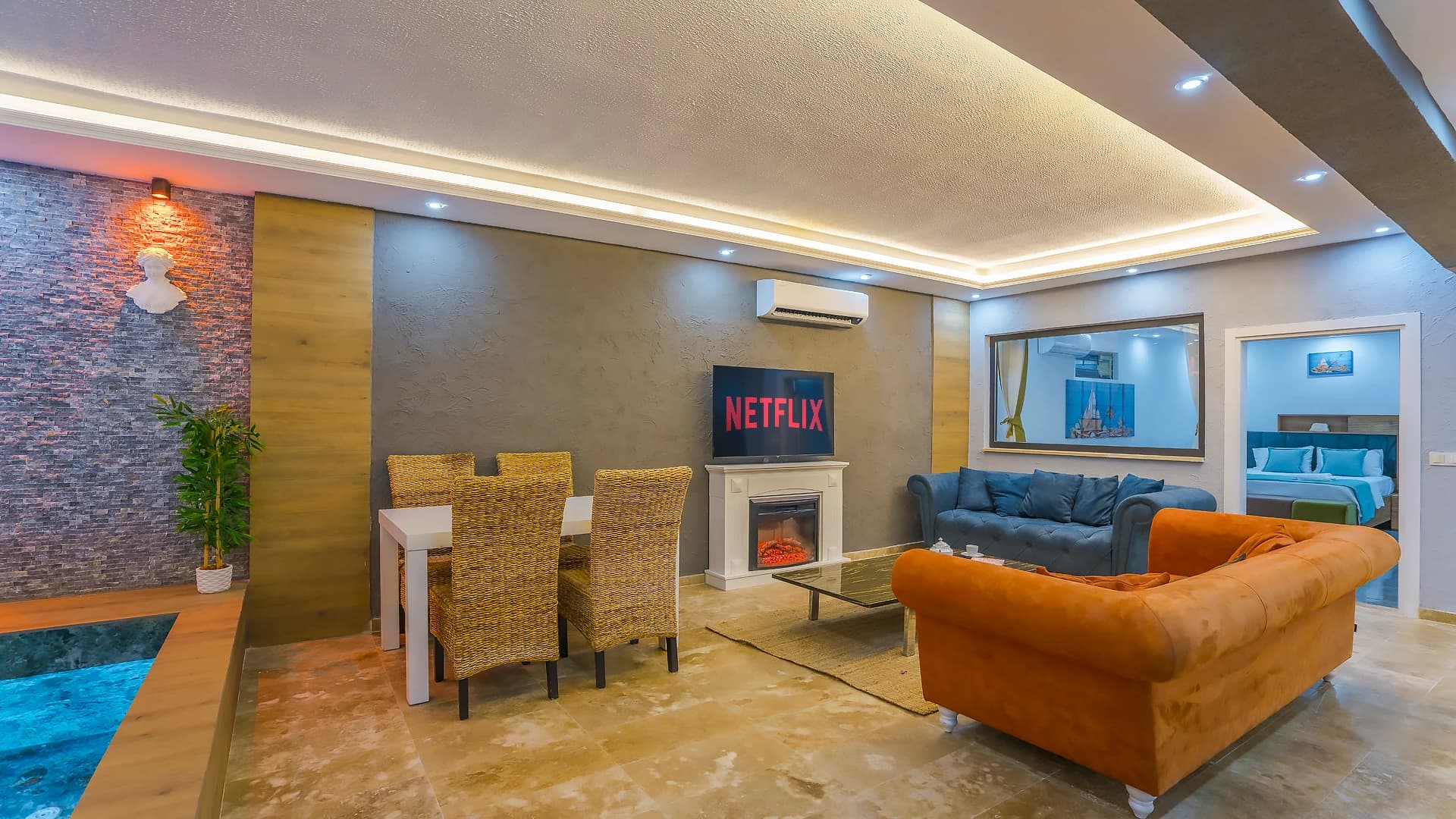 Modern living room with entertainment setup overlooking the indoor pool area.