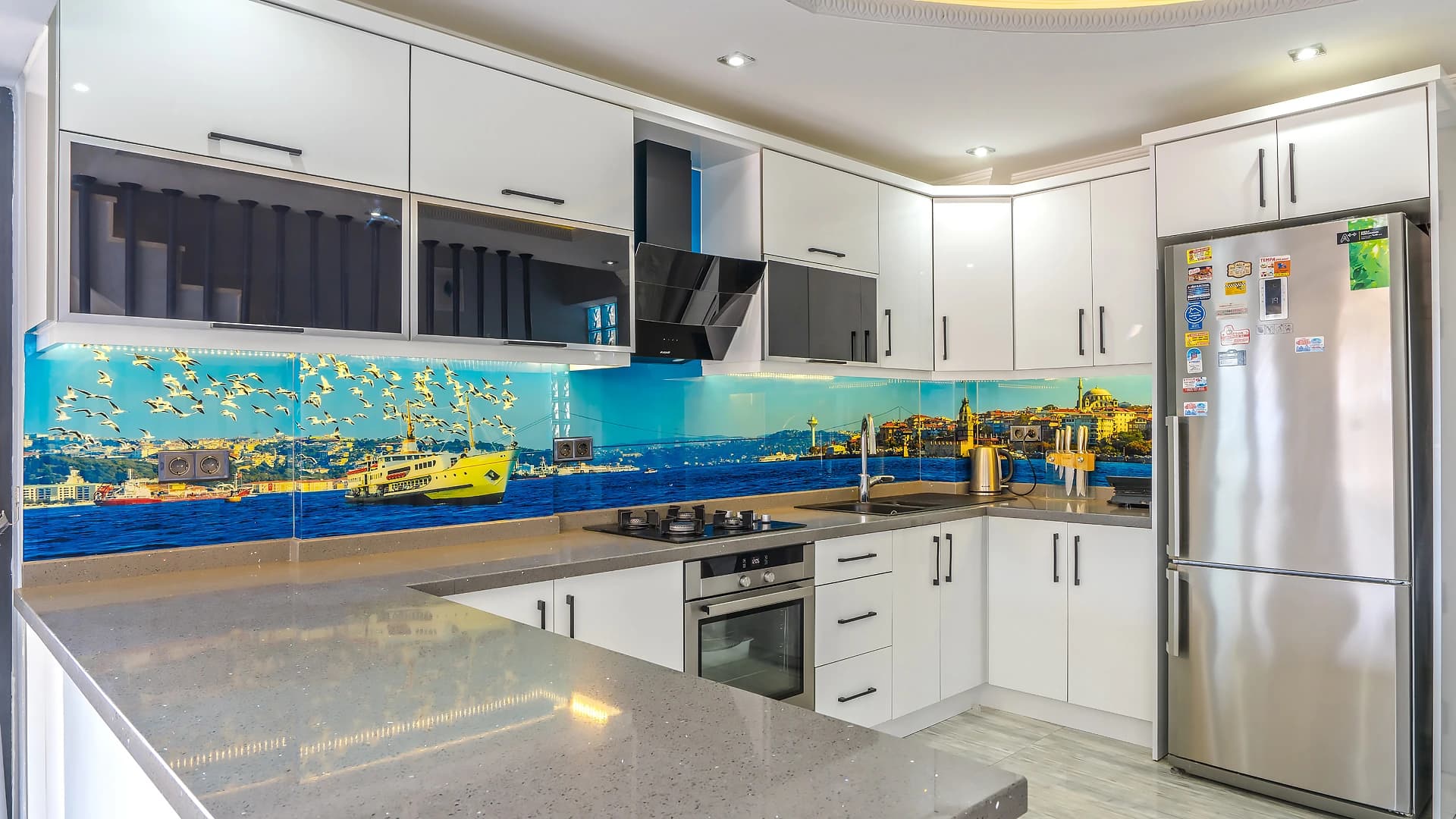 Modern kitchen with white cabinetry and colorful harbor-themed backsplash.
