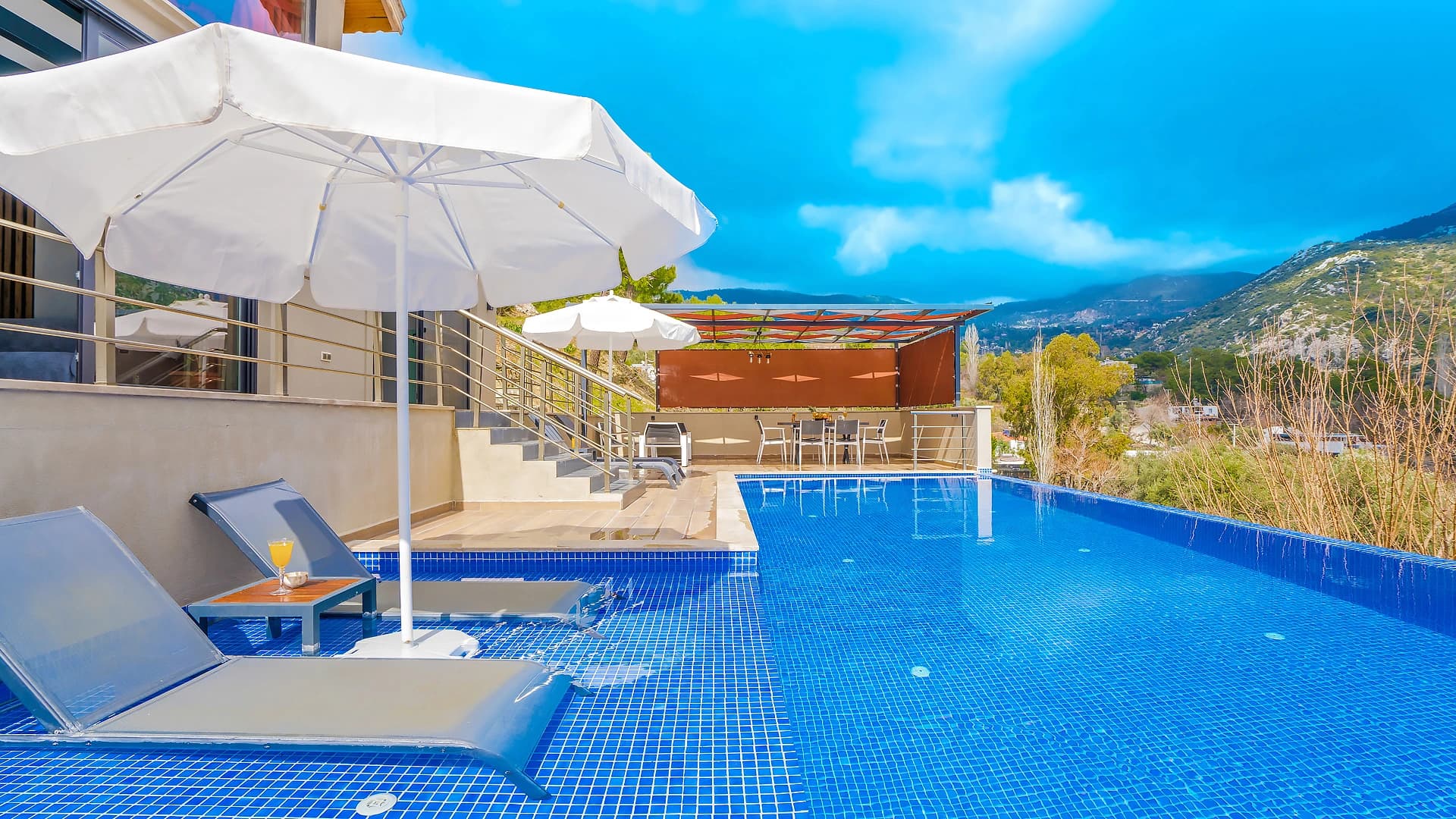Resort-style pool with sun loungers and mountain landscape views.