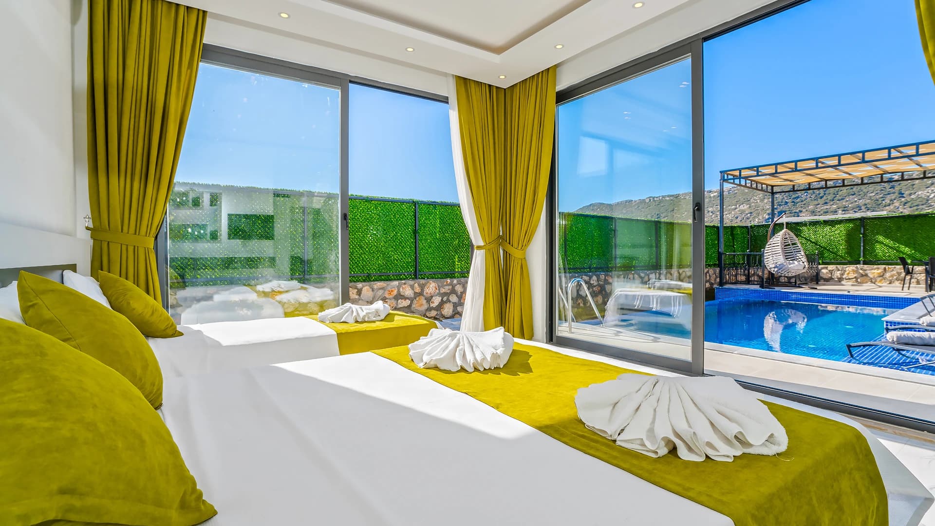 Twin bedroom with direct pool and mountain views through floor-to-ceiling windows.