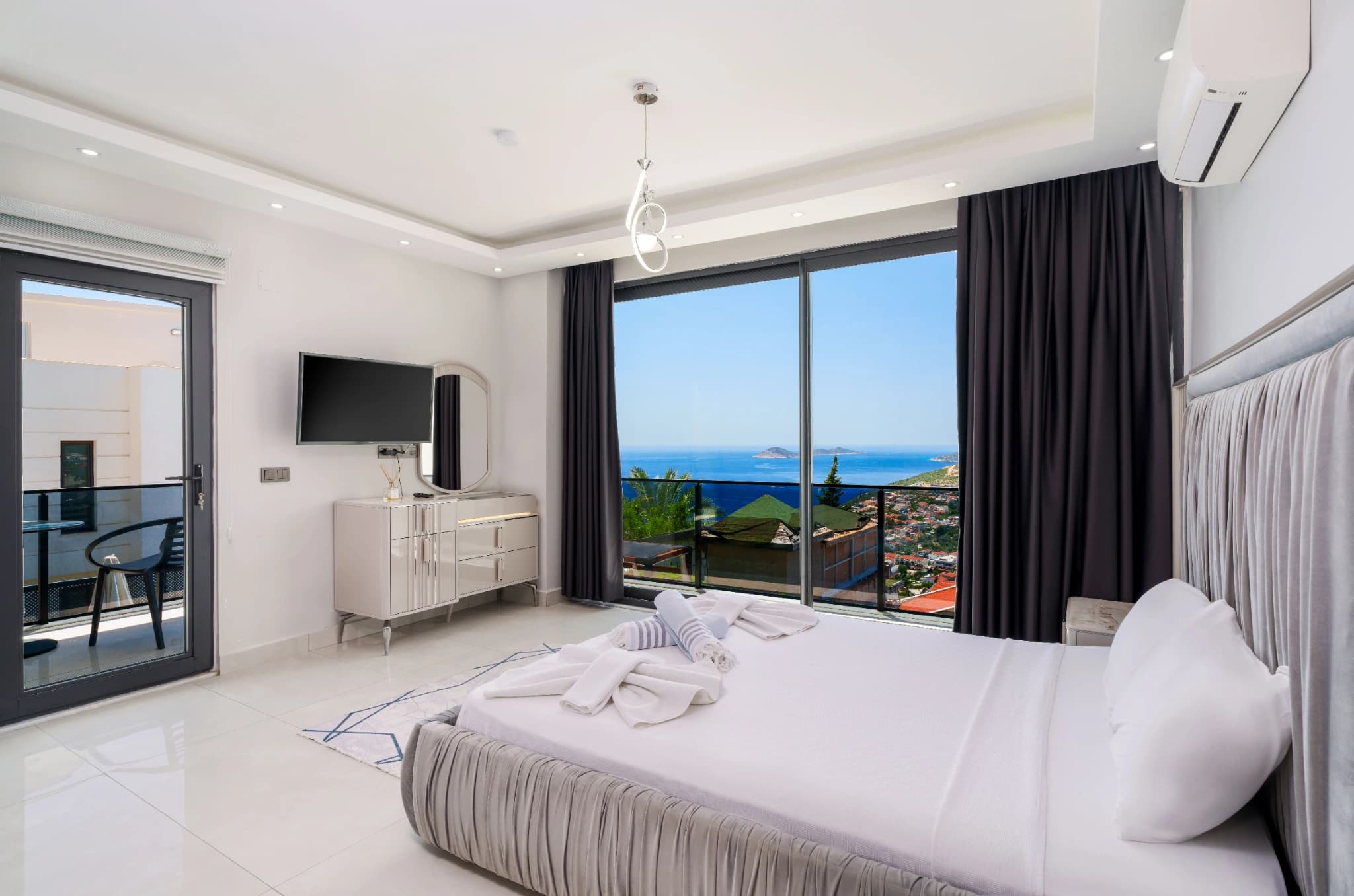 Bright master bedroom with panoramic sea views, king bed, and private balcony access.