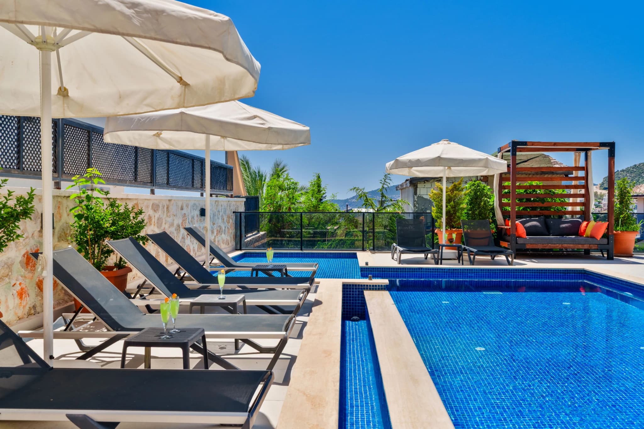 Spacious pool area with lounge chairs, umbrellas, and mountain backdrop.
