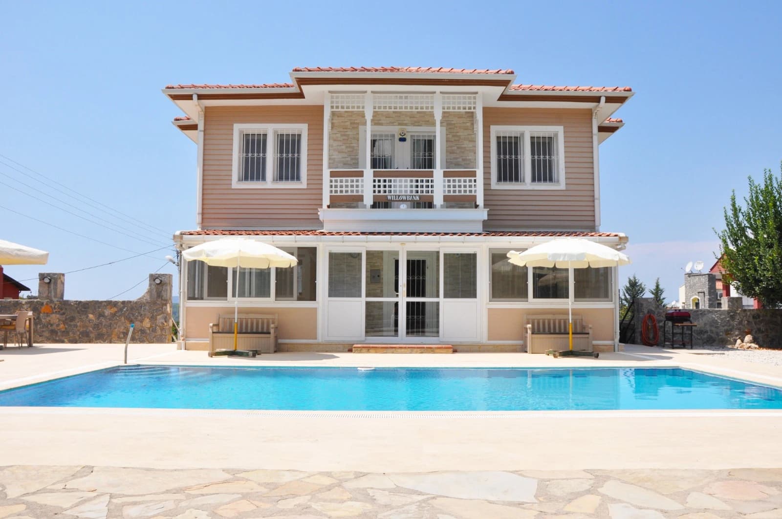 Front elevation of the villa with pool and mountain backdrop.