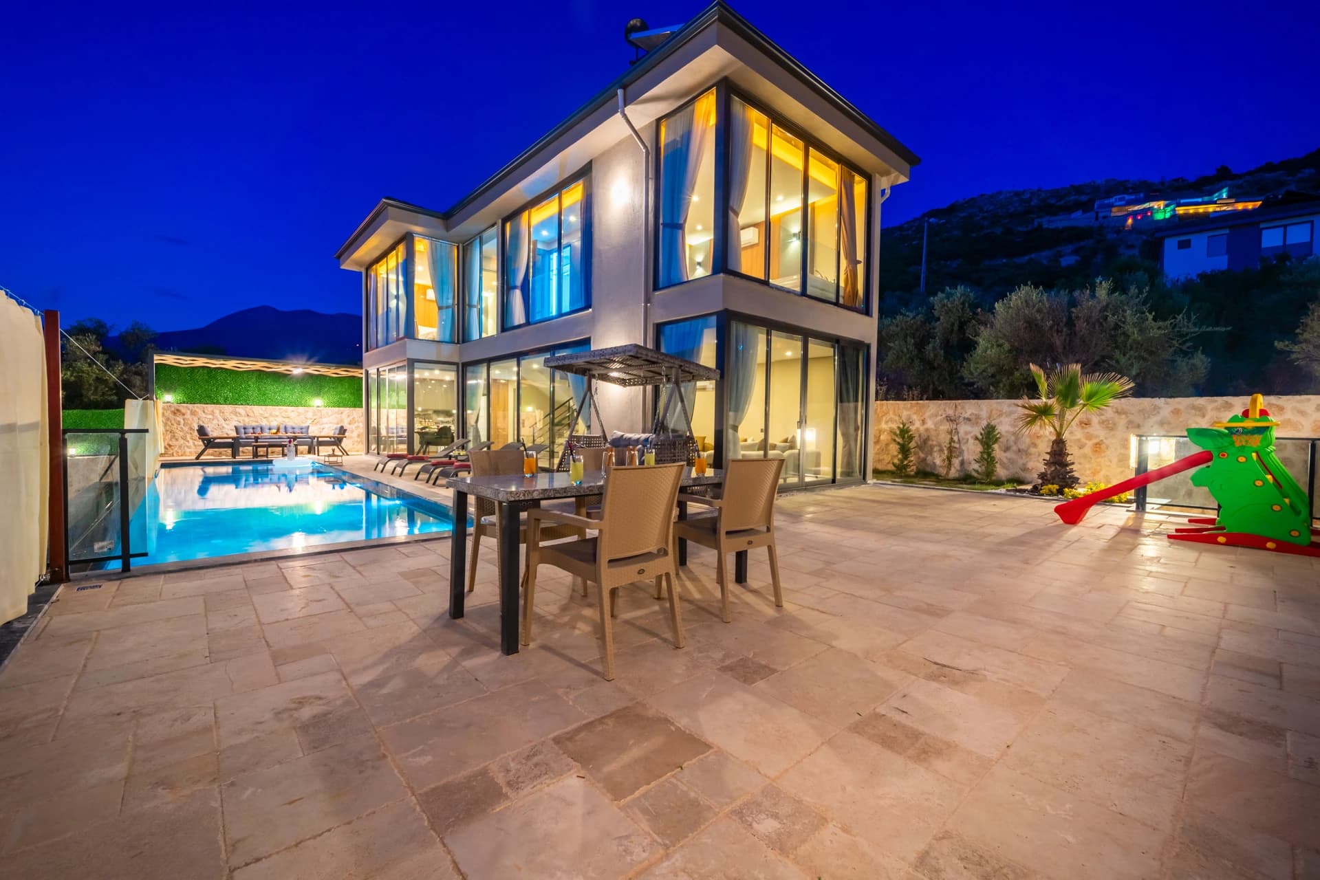 Stunning pool area with adjacent terrace, modern villa, and mountain backdrop.