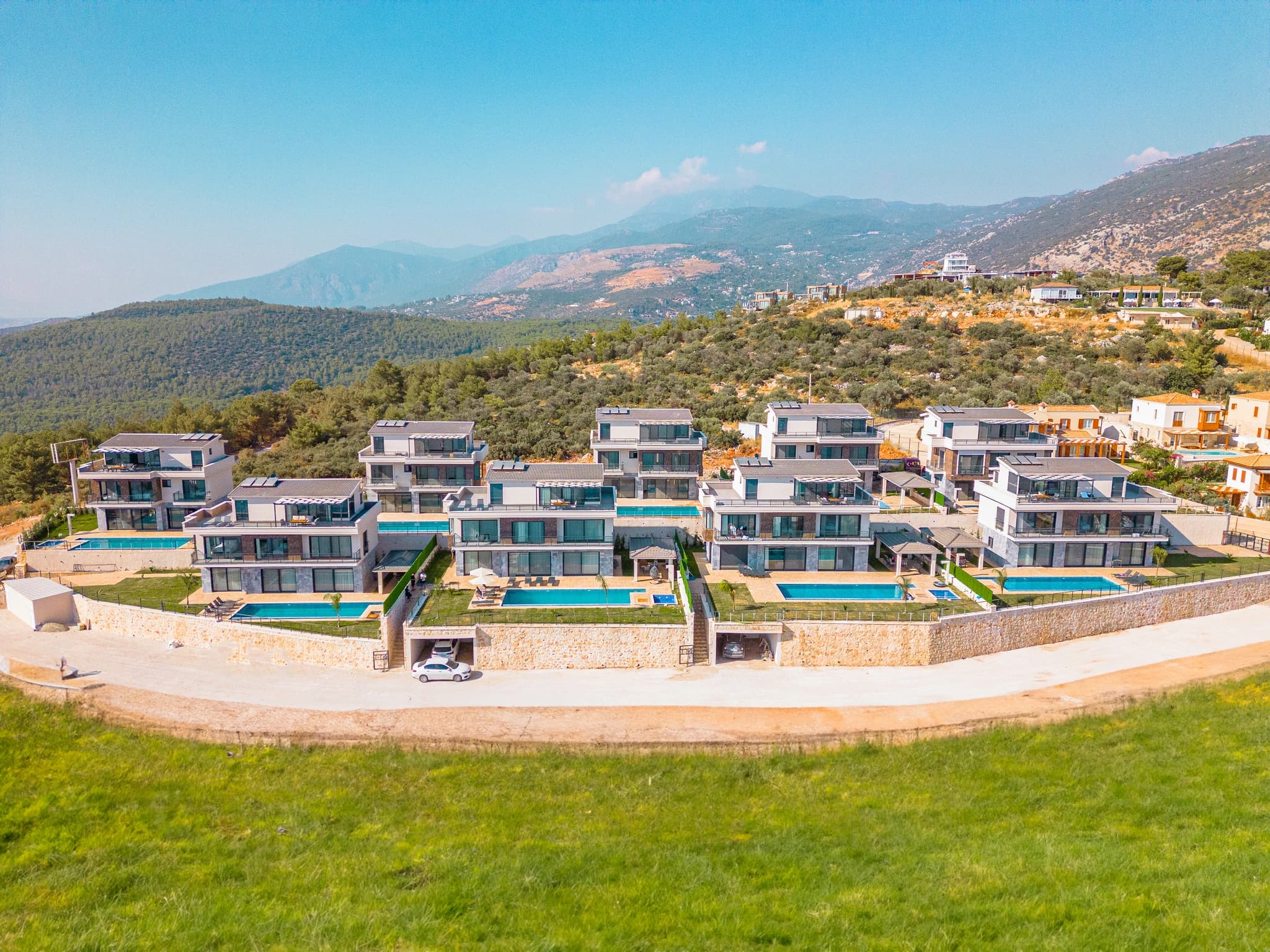 Aerial view of the luxury villa complex nestled in mountainous terrain with individual private pools and contemporary architecture.