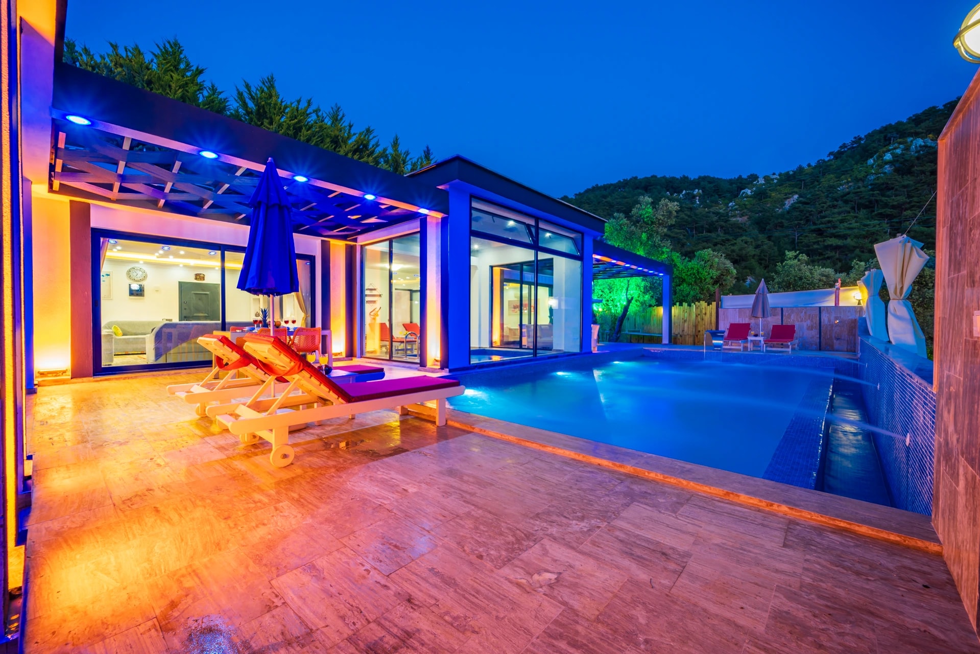 Stunning illuminated pool area with loungers overlooking mountainous landscape.