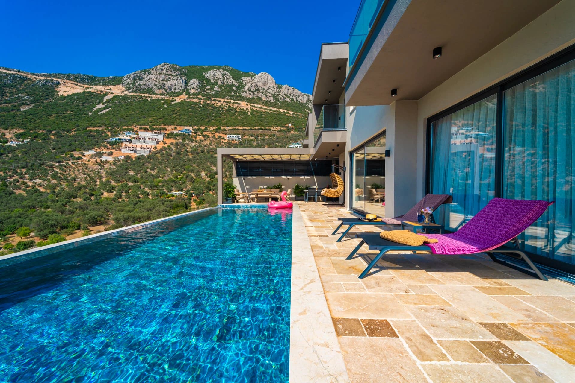 Stunning infinity pool with mountain views and sun loungers on expansive terrace.