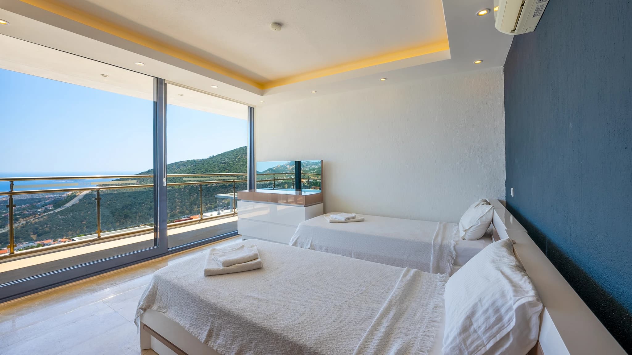 Twin bedroom with stunning sea and mountain views through floor-to-ceiling balcony doors.