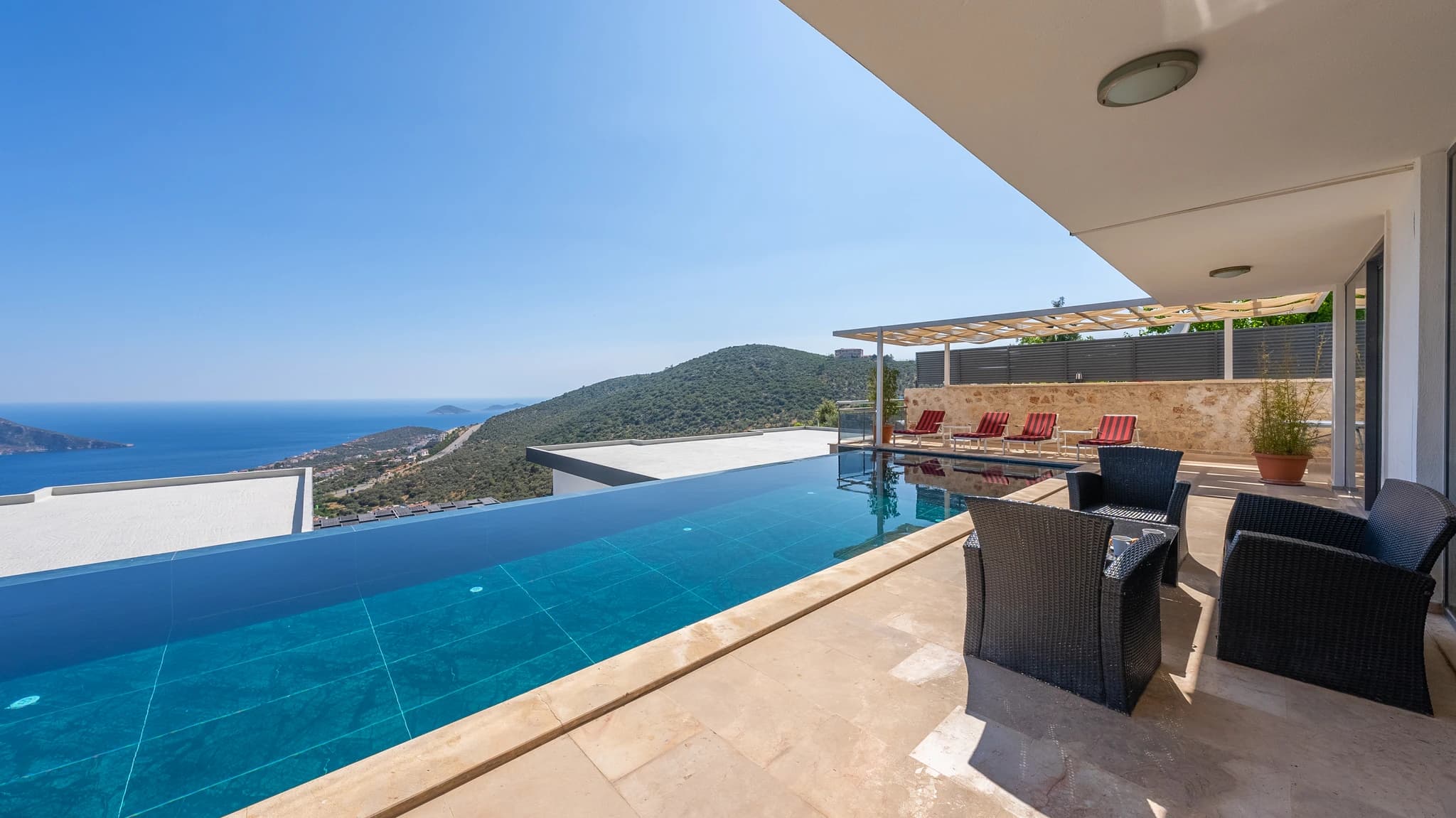 Private pool with breathtaking coastal and mountain views and modern outdoor furniture.
