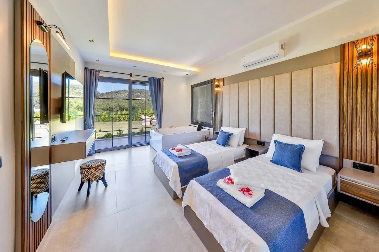 Bright bedroom with three single beds, ensuite facilities, mountain views through glass doors, and contemporary styling.