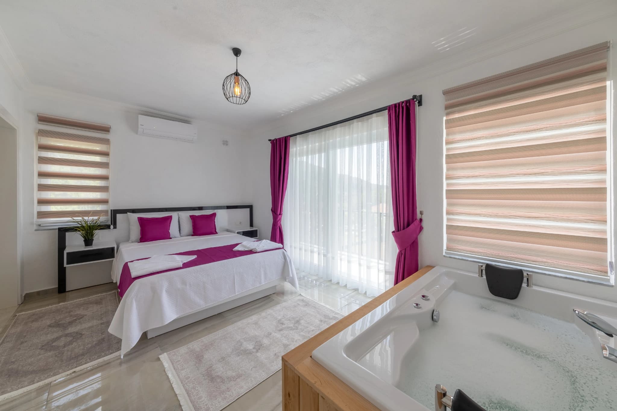 Master bedroom with double bed, modern decor, and ensuite with jacuzzi bathtub and balcony access.