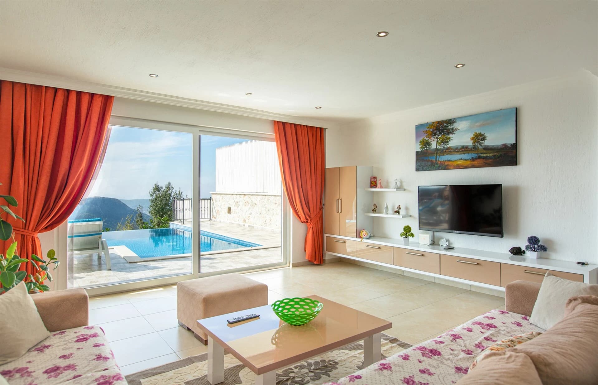 Living room with panoramic infinity pool and mountain views through glass doors.
