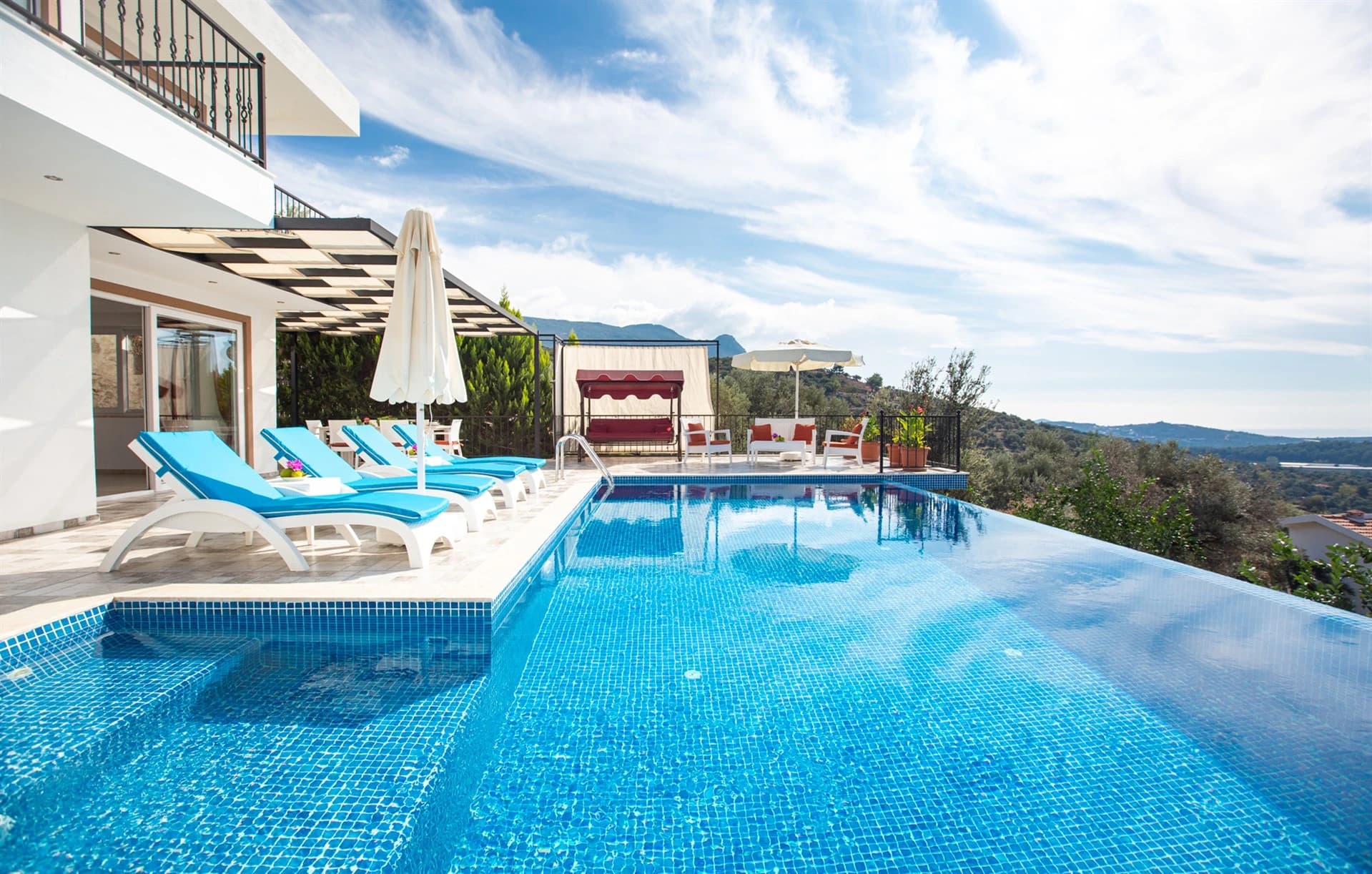Stunning pool overlooking mountains with sun loungers and pergola shade.