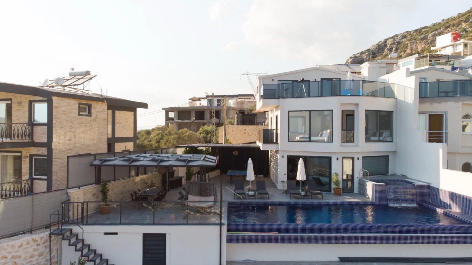 Wide shot of contemporary villa exterior with multiple pool levels and terraces.