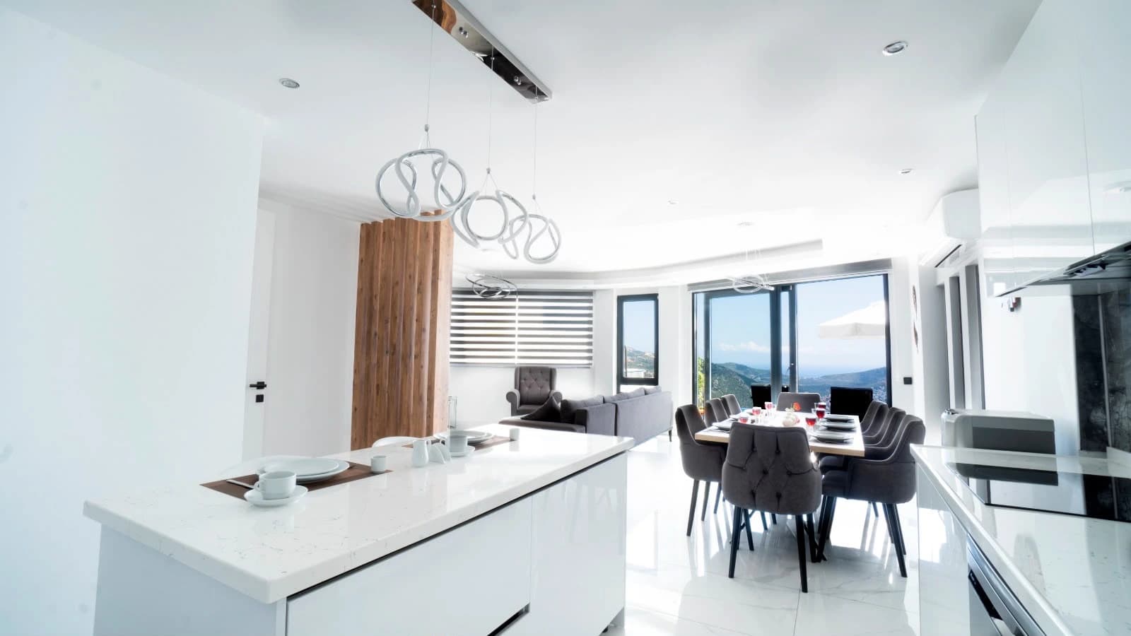 Modern open-plan kitchen with island and panoramic sea/mountain views.
