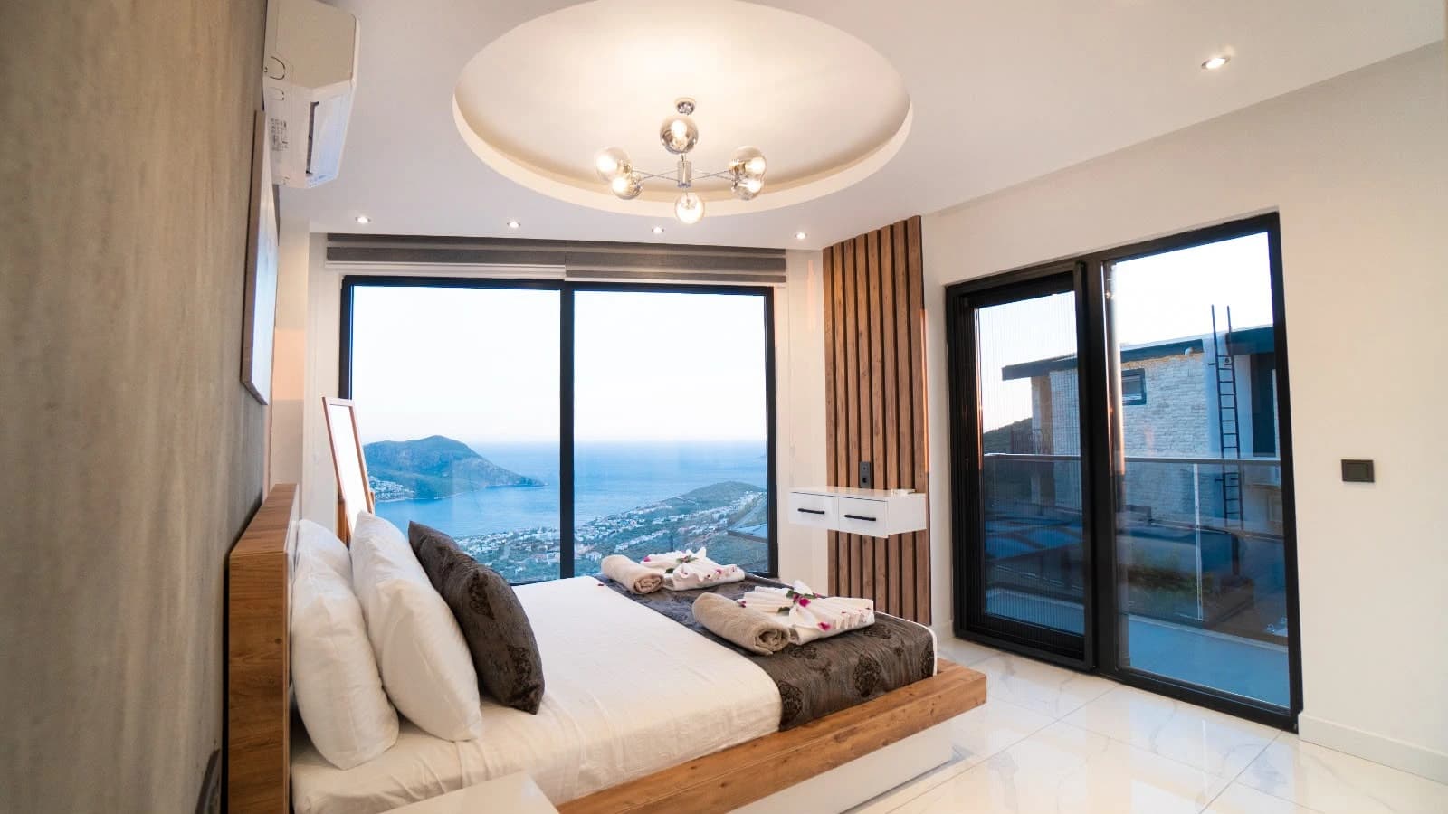 Spacious master bedroom with king bed and stunning sea and mountain views from terrace doors.