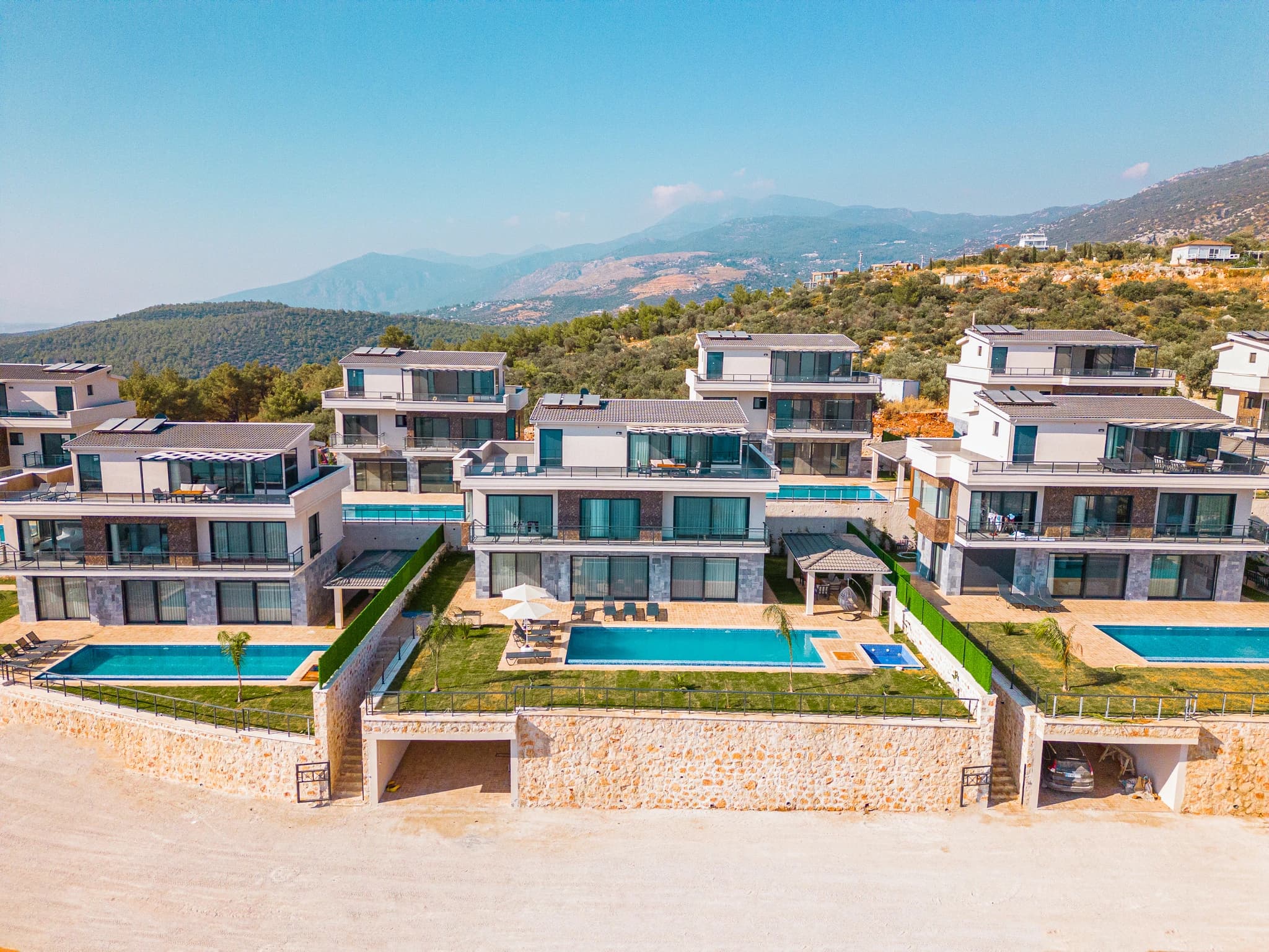 Aerial view of the luxury villa complex nestled in the mountainous landscape with private pools and contemporary design.