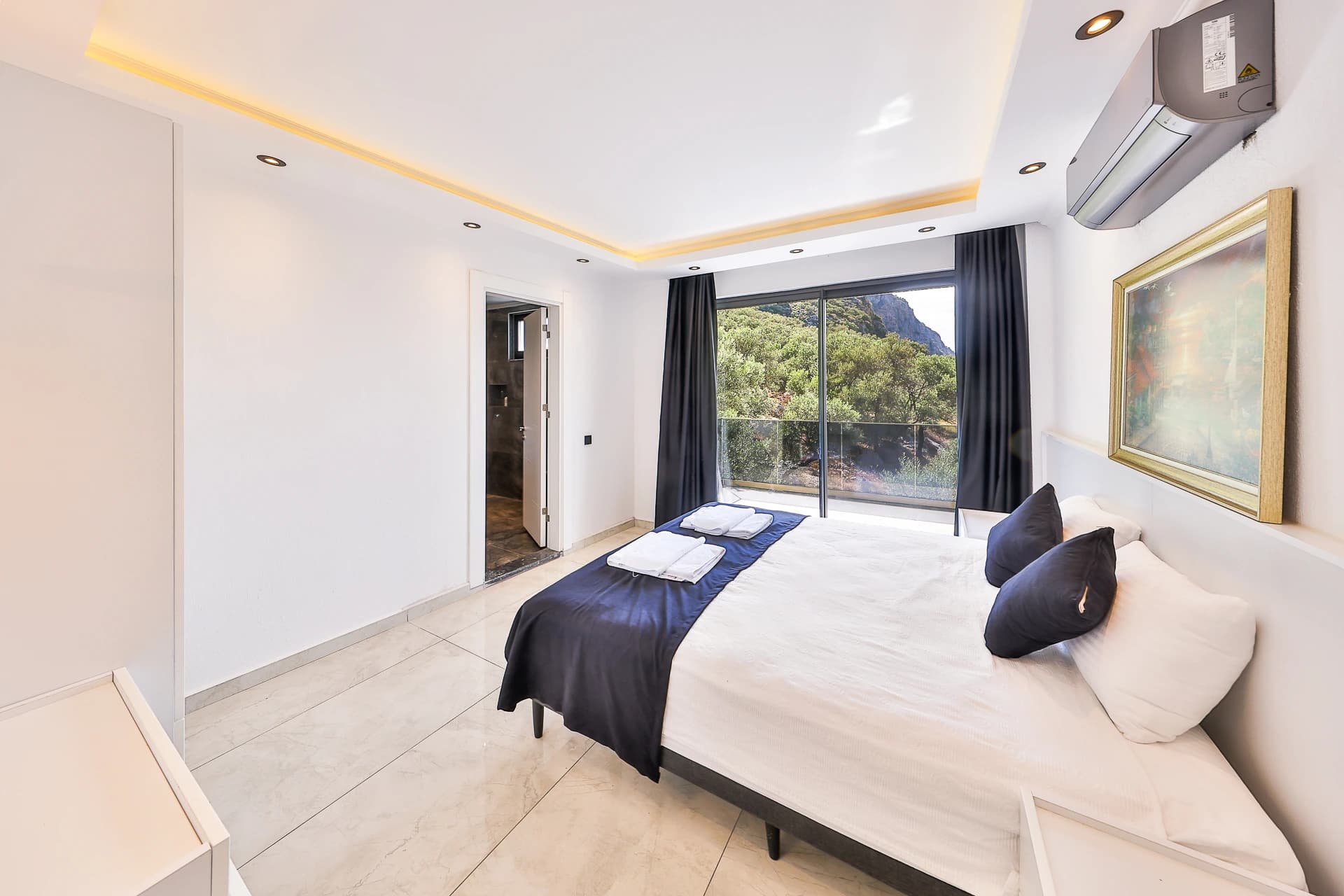 Modern bedroom with king bed, AC, and access to mountain-view balcony.