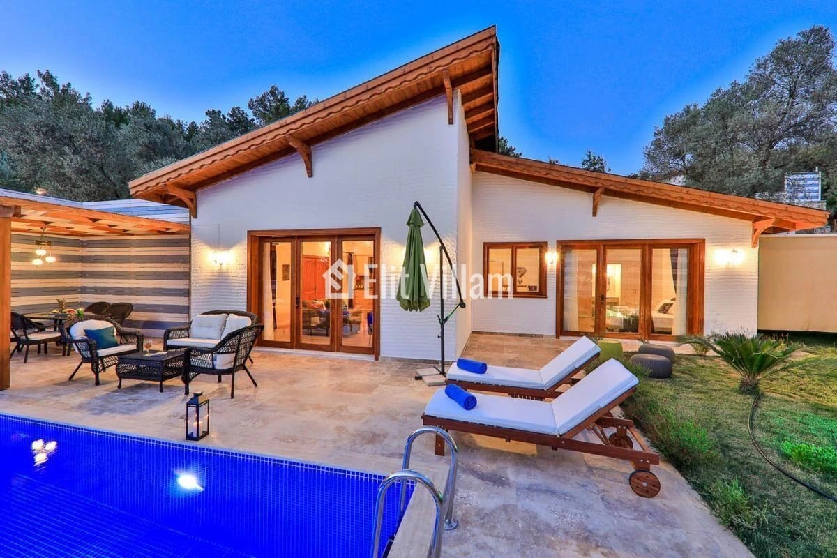 Twilight view of the villa exterior with illuminated private pool and furnished terrace.