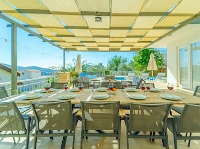 Covered terrace with outdoor dining table and expansive mountain vistas.