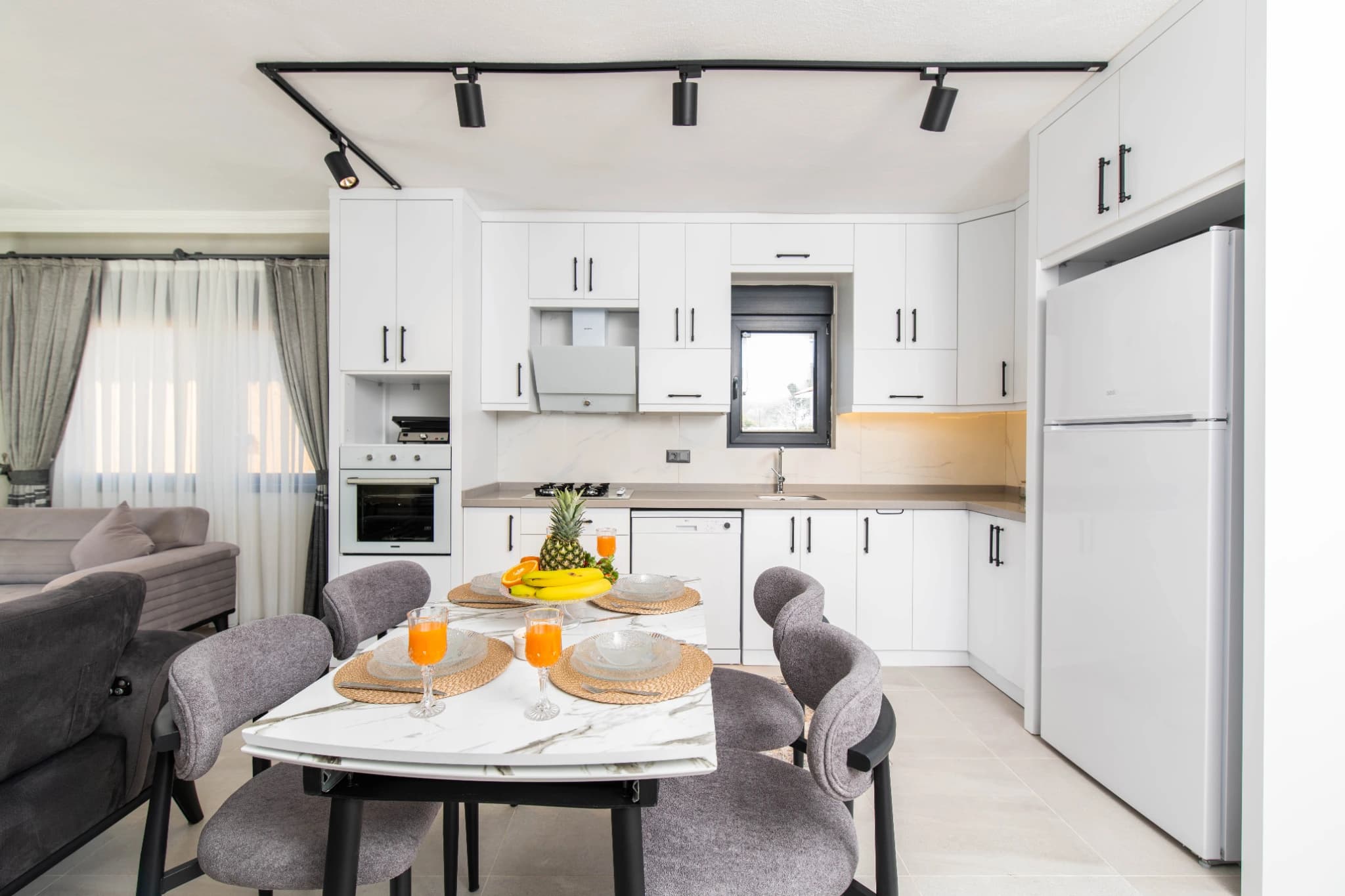 Open-plan kitchen and dining area with modern appliances and seating for four.