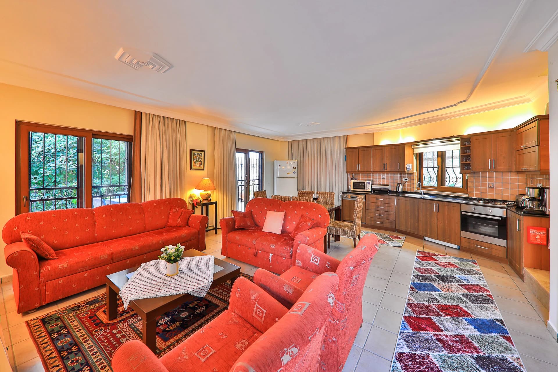 Open-plan living room with red seating, integrated kitchen, and garden access.