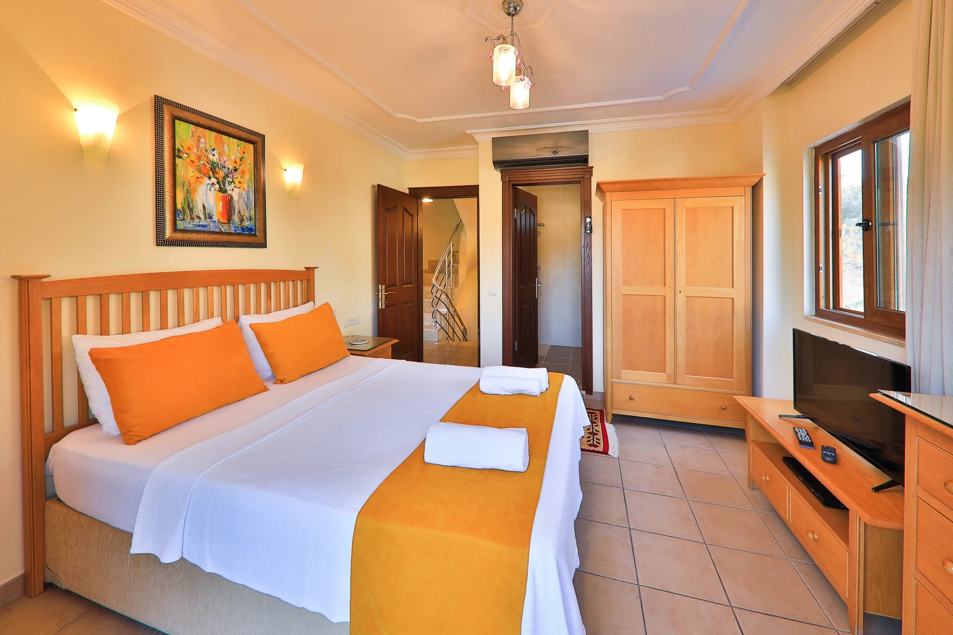 Bright bedroom with queen bed, TV, and access to ensuite bathroom.
