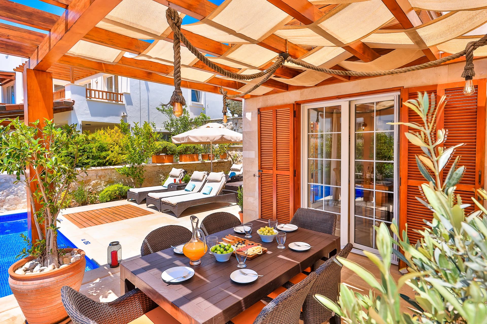 Covered dining terrace with table seating and adjacent lounging areas by the pool.