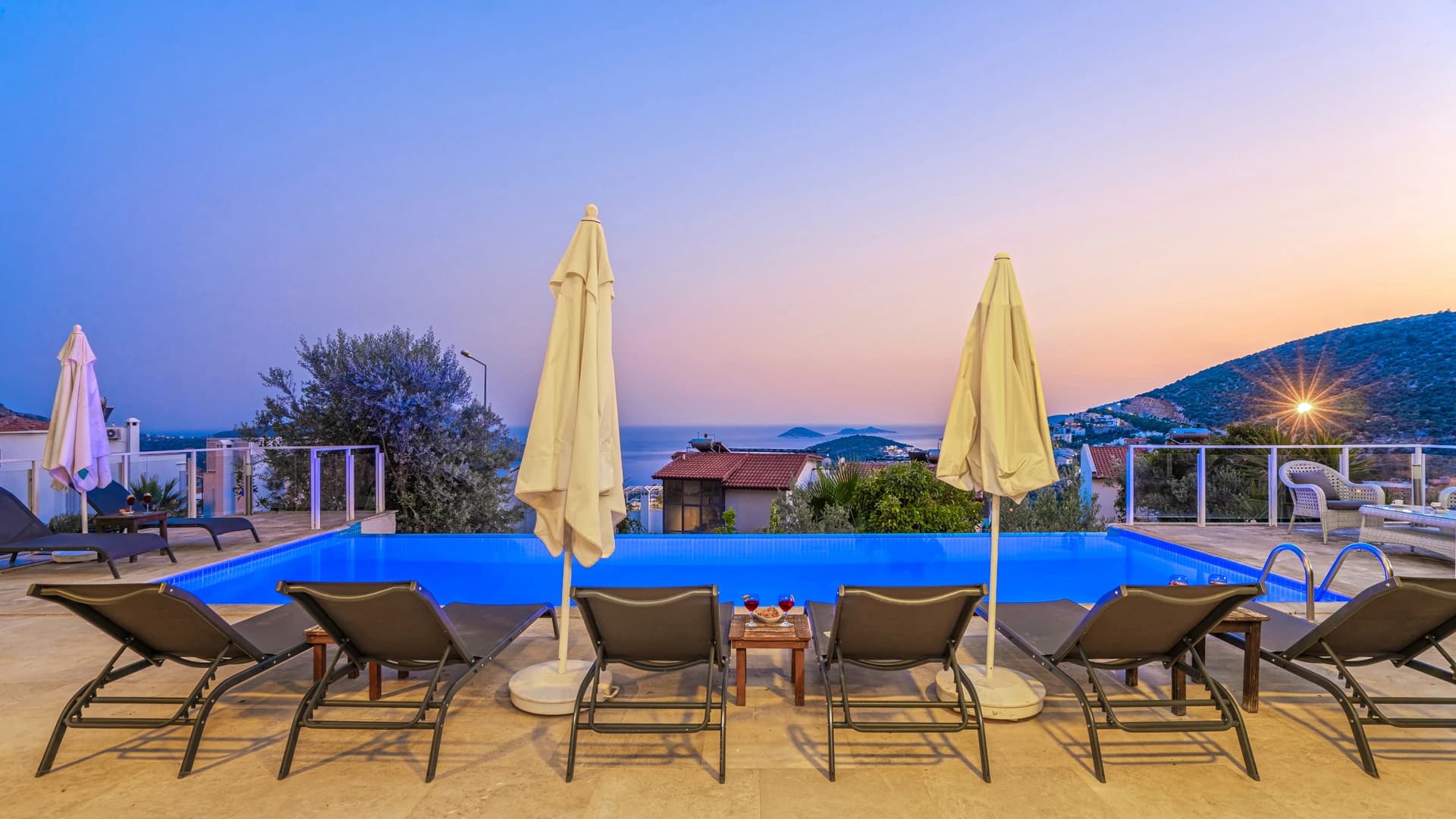 Resort-style pool area with lounge chairs and parasols at golden hour.