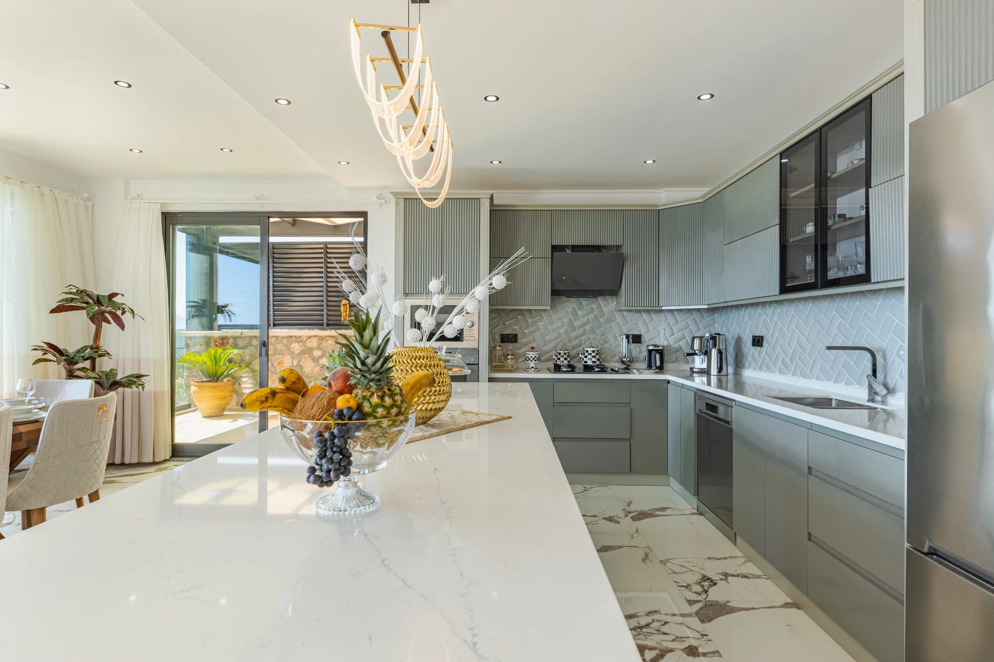 Contemporary kitchen with white marble island, dark cabinetry, and seamless indoor-outdoor flow.